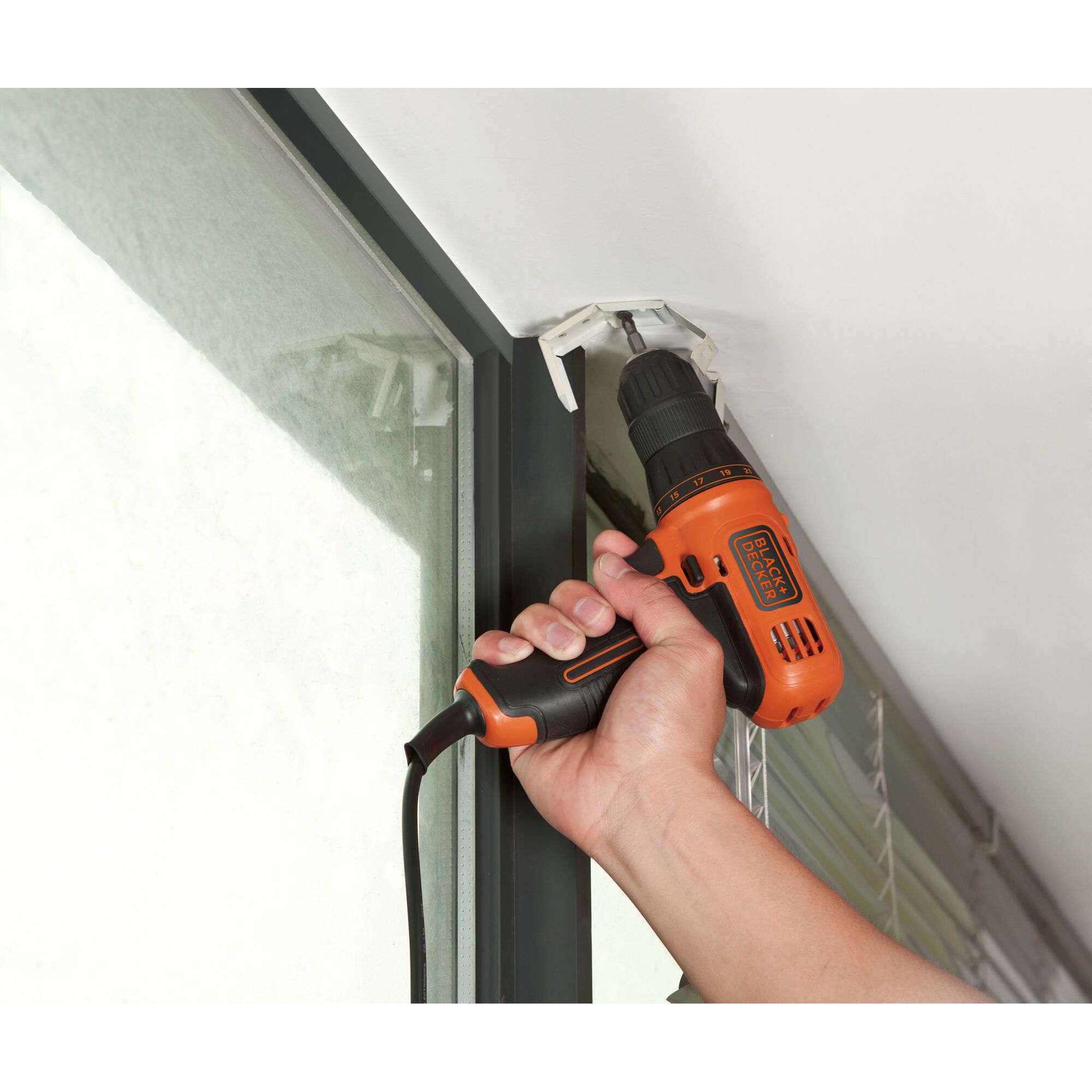BLACKDECKER KR112 orange corded drill used to install bracket near window.