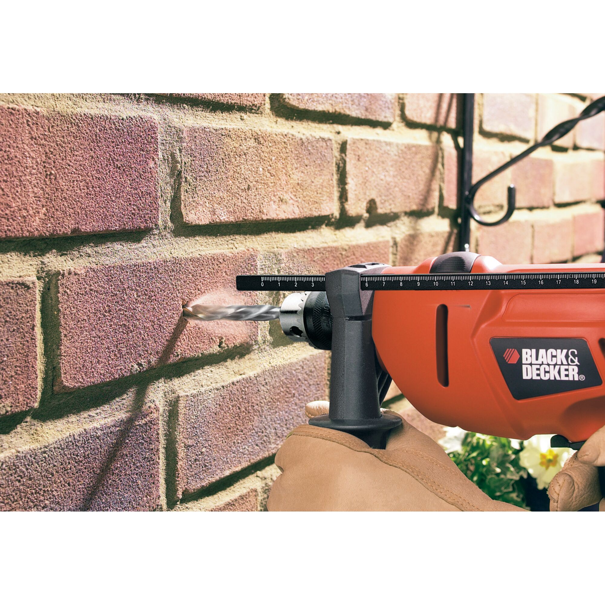 BLACKDECKER KR454RE drill in action drilling into brick wall, close-up of tool and gloved hand.