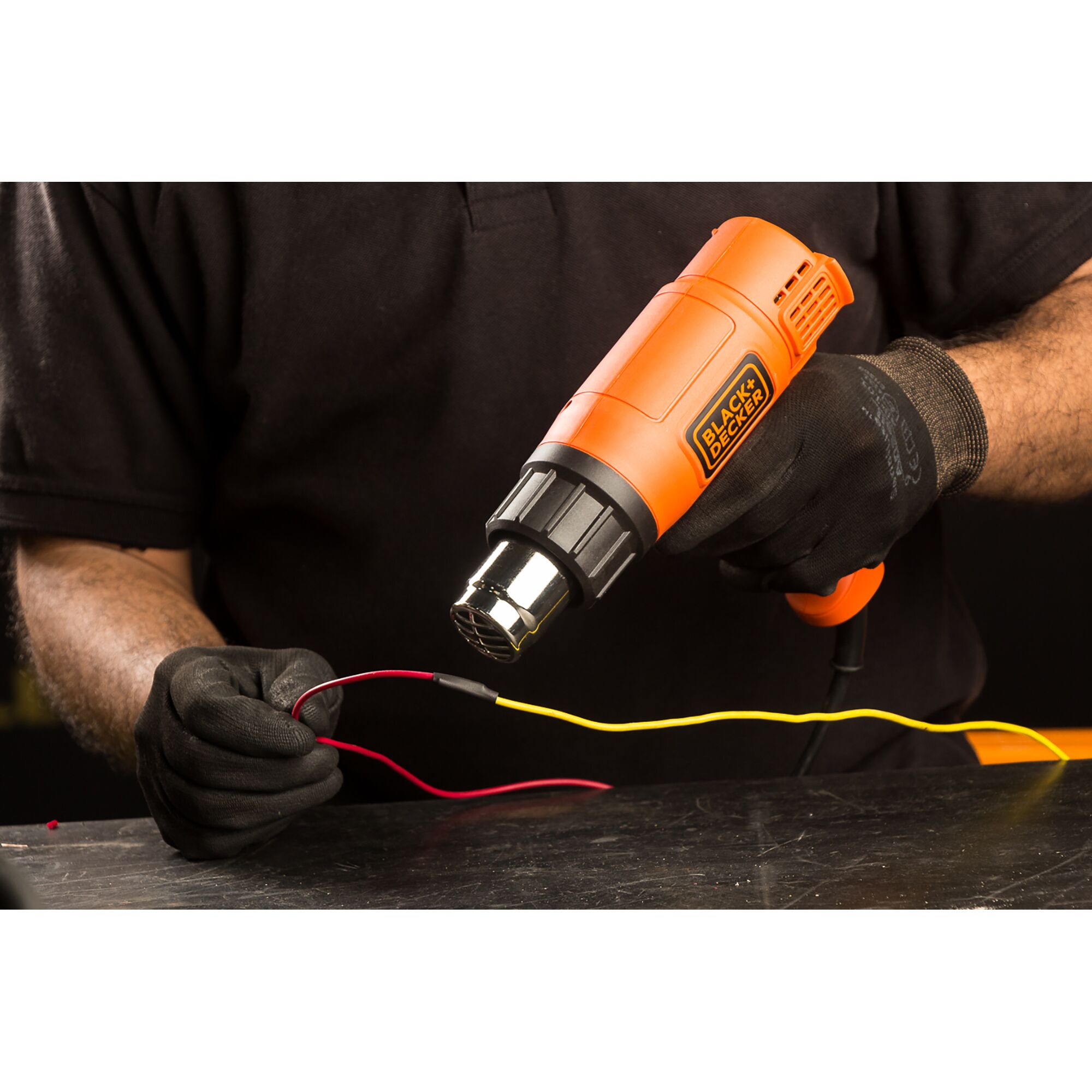 BLACKDECKER KX1800 orange heat gun used for wire work on a tabletop, close-up.