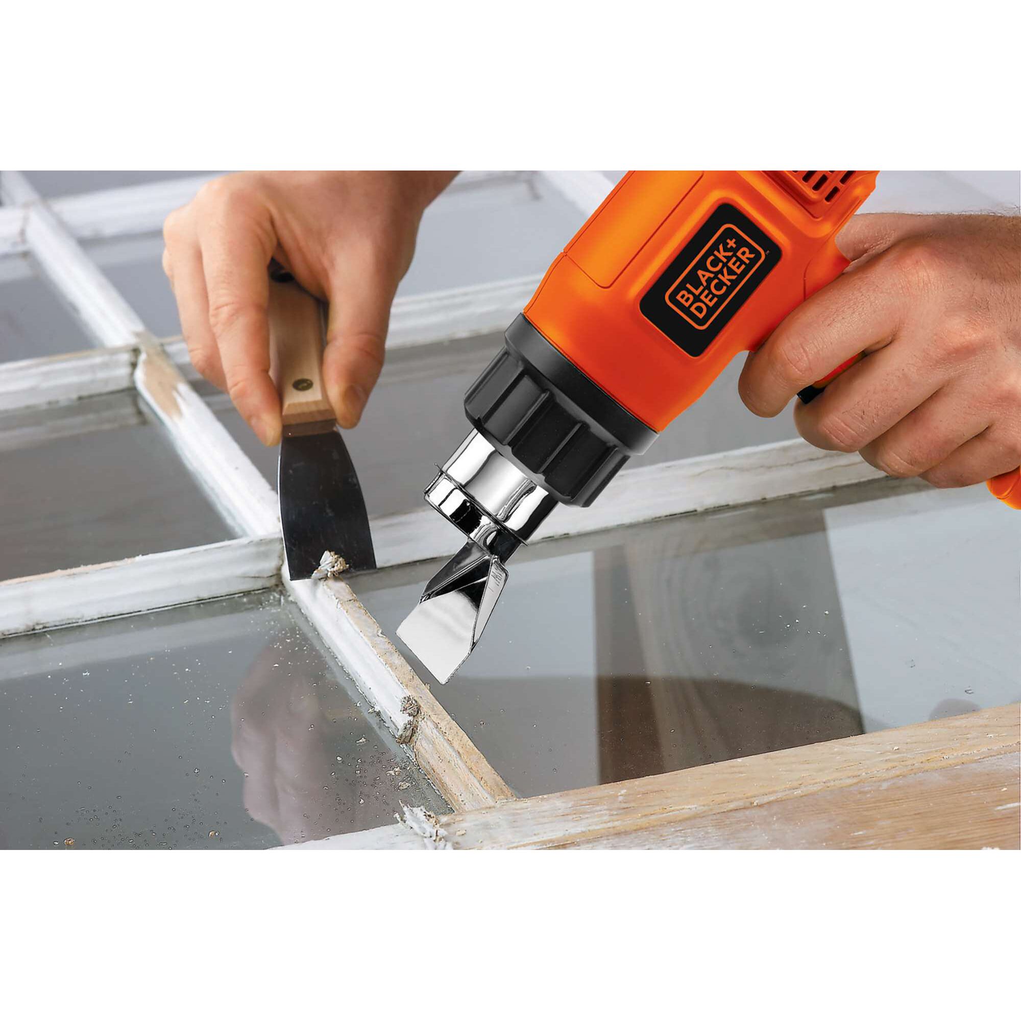 BLACKDECKER KX1800 heat gun in use for paint removal on window frame with scraper tool.