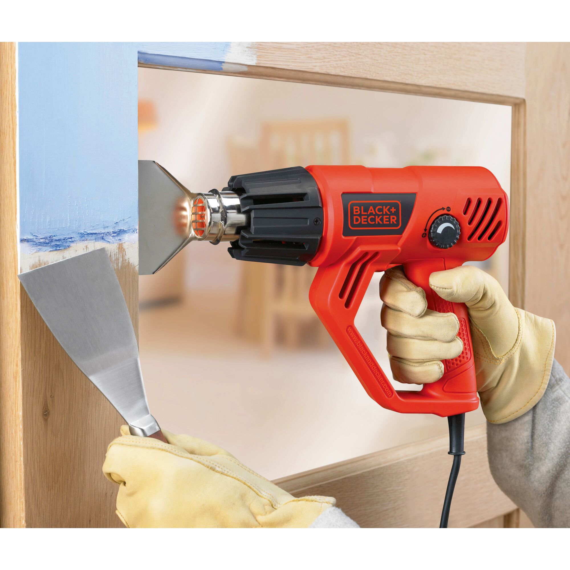 BLACKDECKER KX2001K heat gun in use for paint removal, close-up of tool and gloved hands.