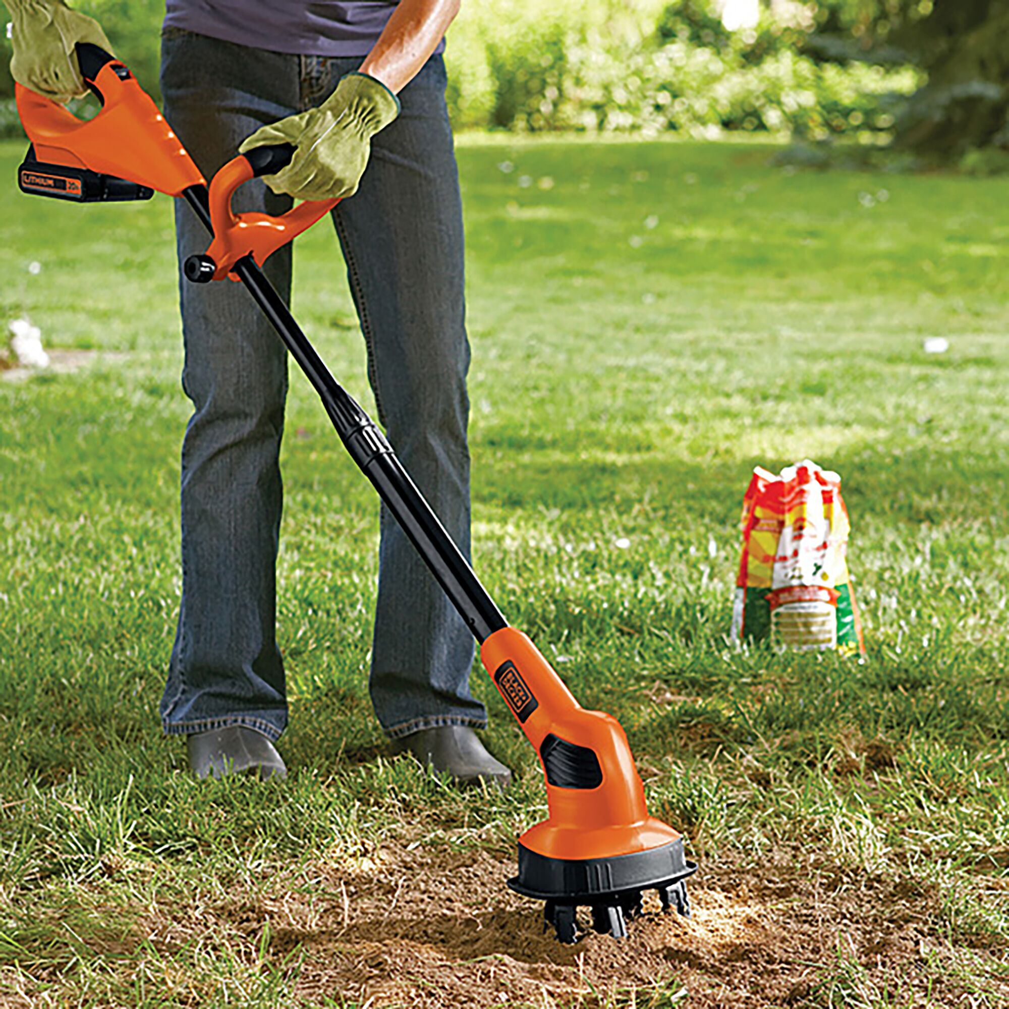 Photo of BLACKDECKER LGC120N cordless garden cultivator with orange handle used on lawn.