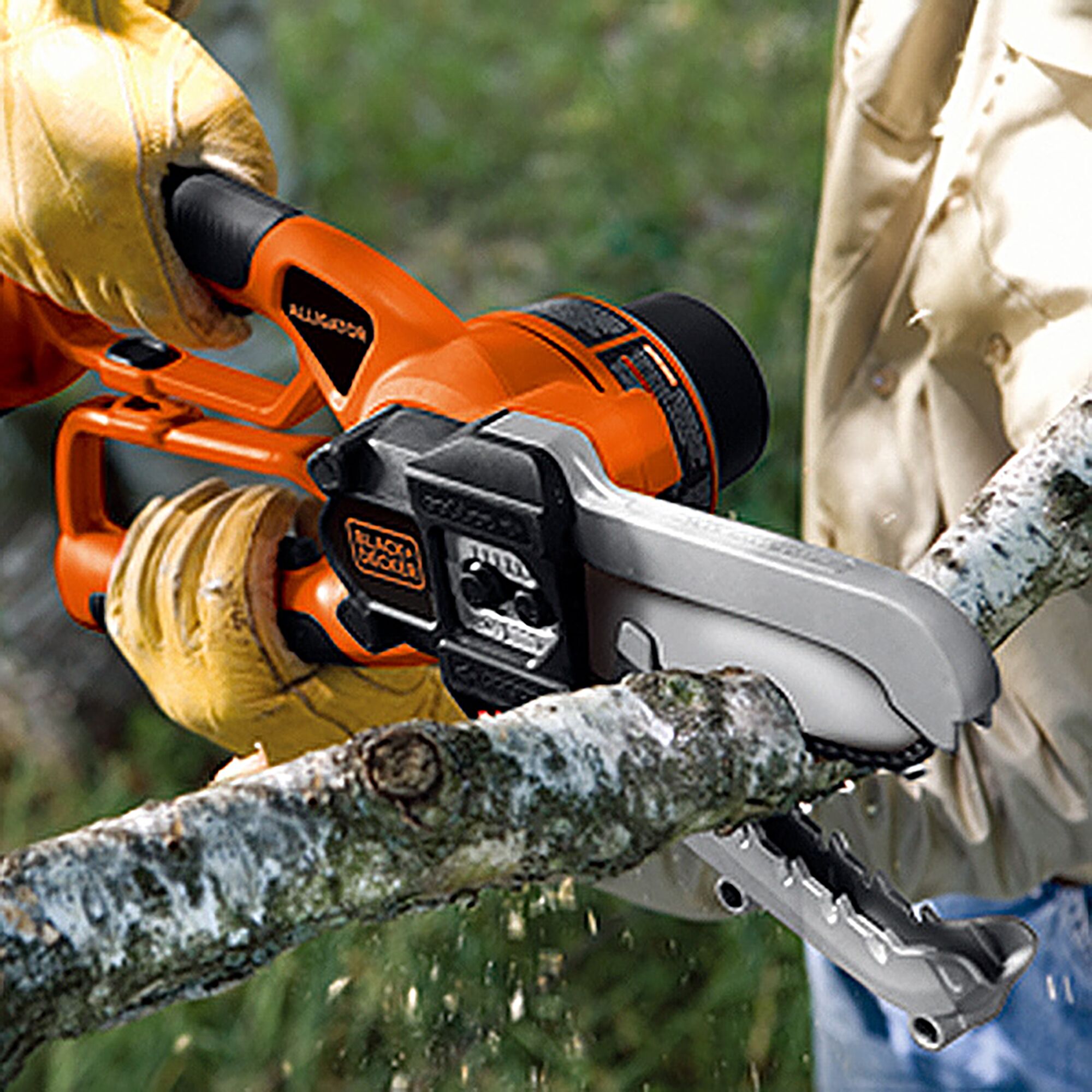 BLACKDECKER LLP18BN photography of orange and black cordless chainsaw cutting a tree branch outdoors.
