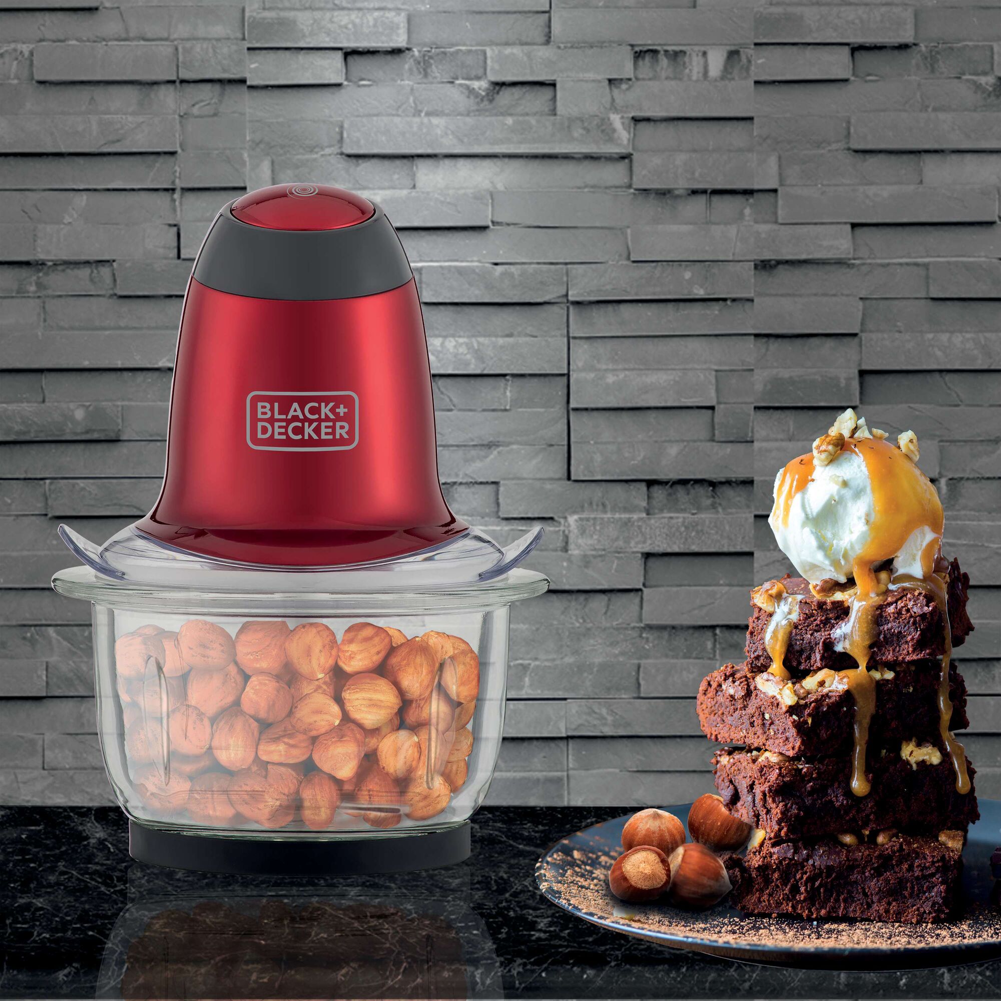 BLACK+DECKER MP200V food chopper with red body and glass bowl filled with hazelnuts, next to a dessert stack.
