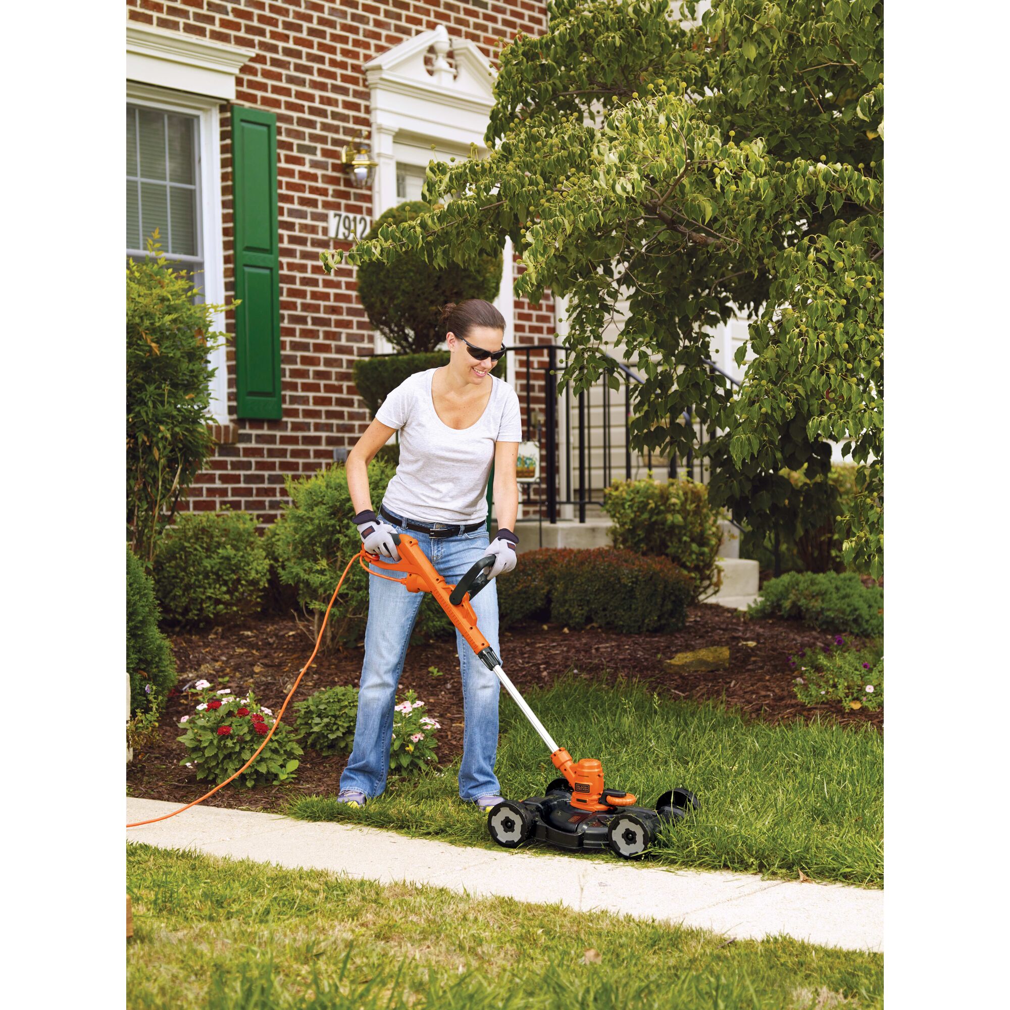 A woman is using a BLACK+DECKER String Trimmer/Edger & Lawn Mower in the garden.