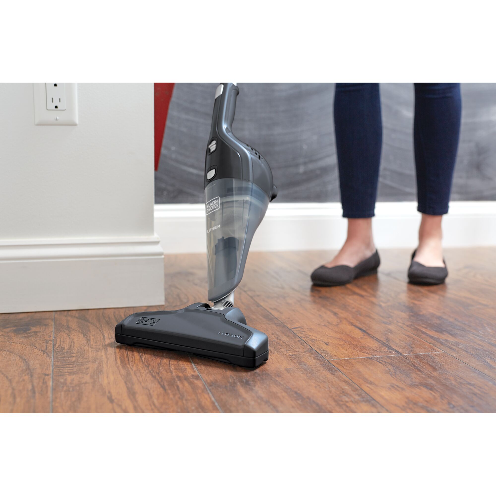 BLACKDECKER NSVA315J cordless stick vacuum in use on wood floor, person standing nearby.
