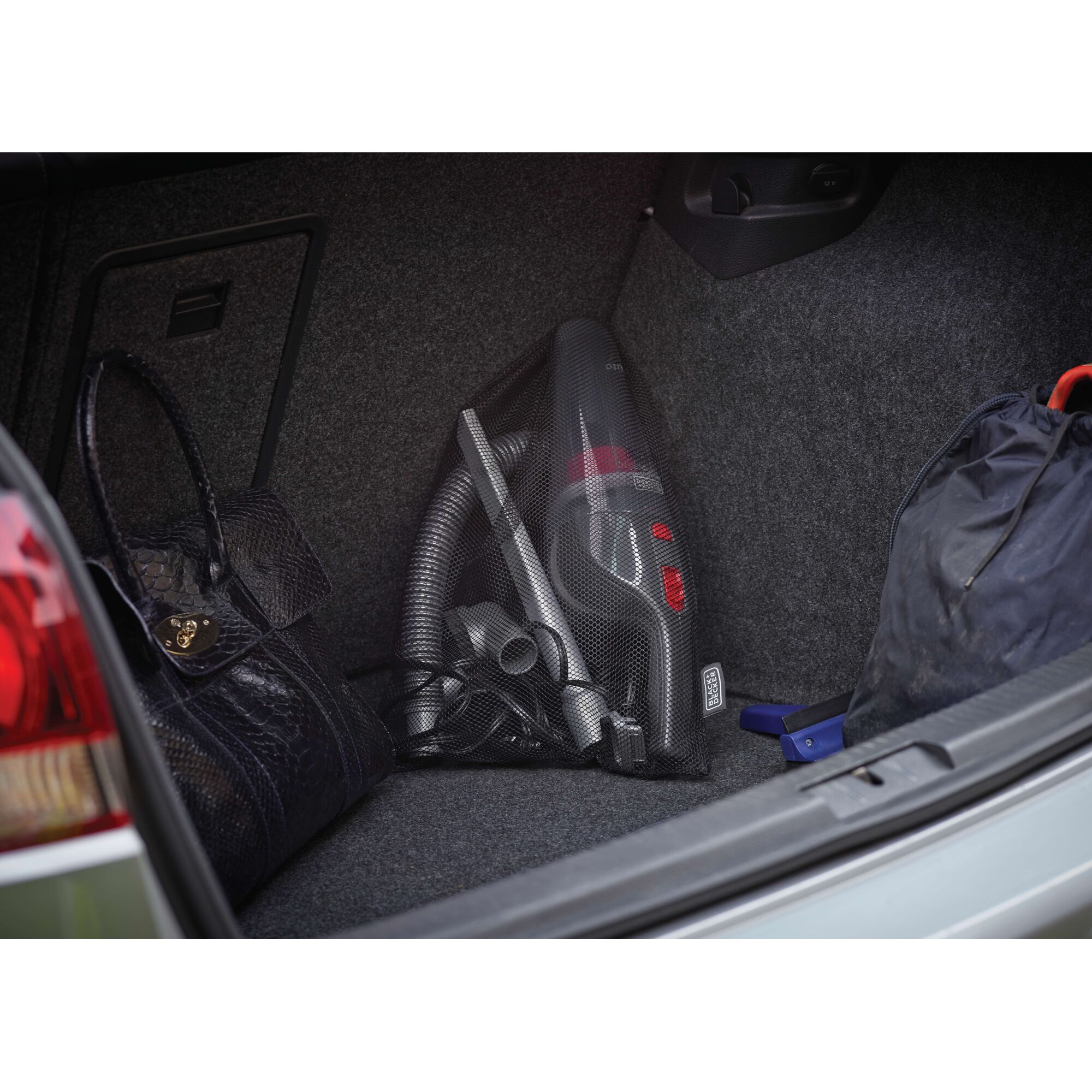BLACKDECKER NV1210AV portable vacuum in car trunk, visible with hose and accessories, next to bags.