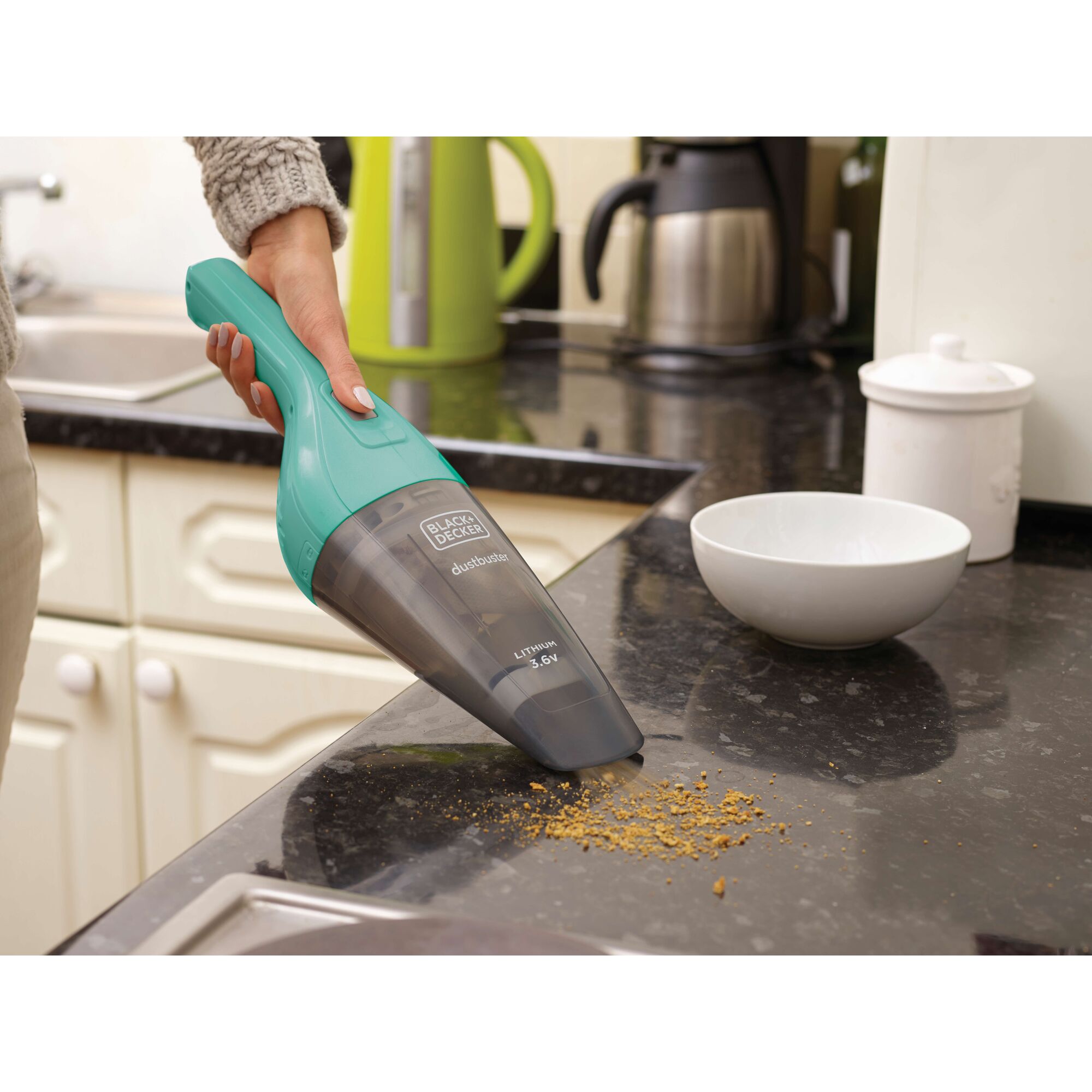 BLACKDECKER NVB115JM-B1 turquoise handheld vacuum cleaner cleaning crumbs on kitchen counter.