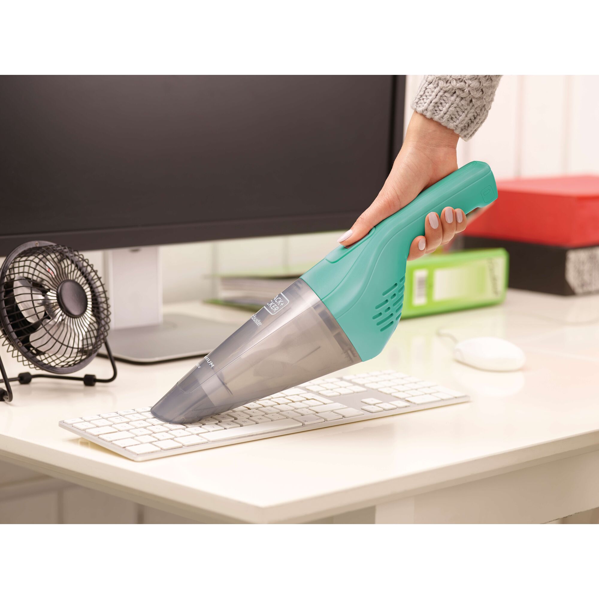 BLACKDECKER NVB115JM-B1 handheld vacuum cleaning a keyboard on a desk, turquoise and grey finish.