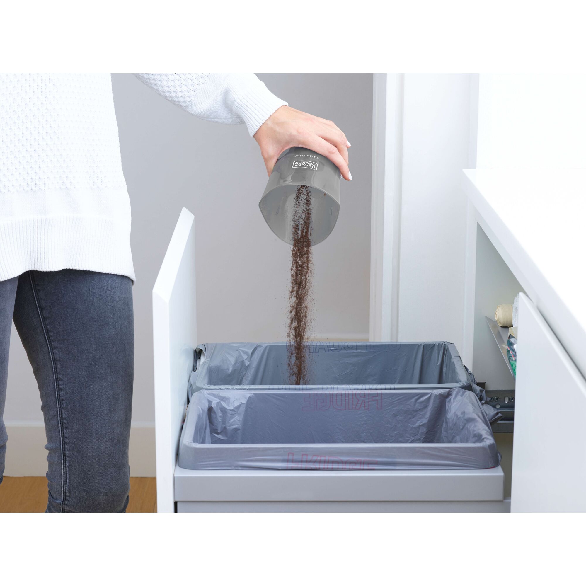 Photo of BLACKDECKER NVB115JM-B1 dust compartment being emptied into a kitchen trash bin.