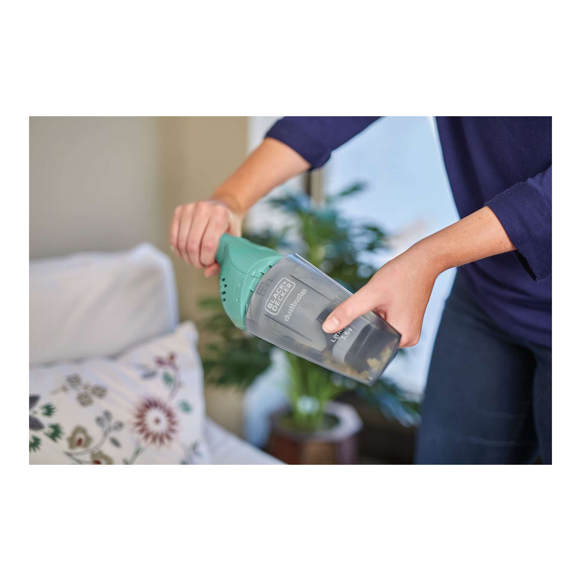 BLACK+DECKER NVB115JM-B1 handheld vacuum, teal and gray, being used to clean a couch.