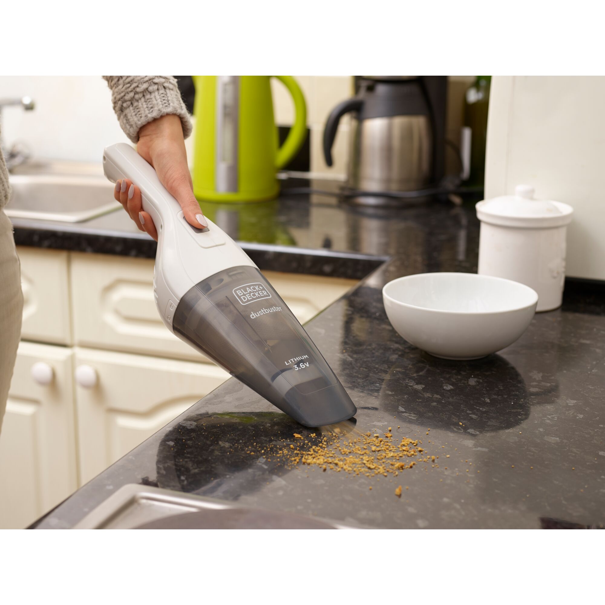 BLACKDECKER NVB115J handheld vacuum cleaning crumbs on kitchen counter near white bowl.