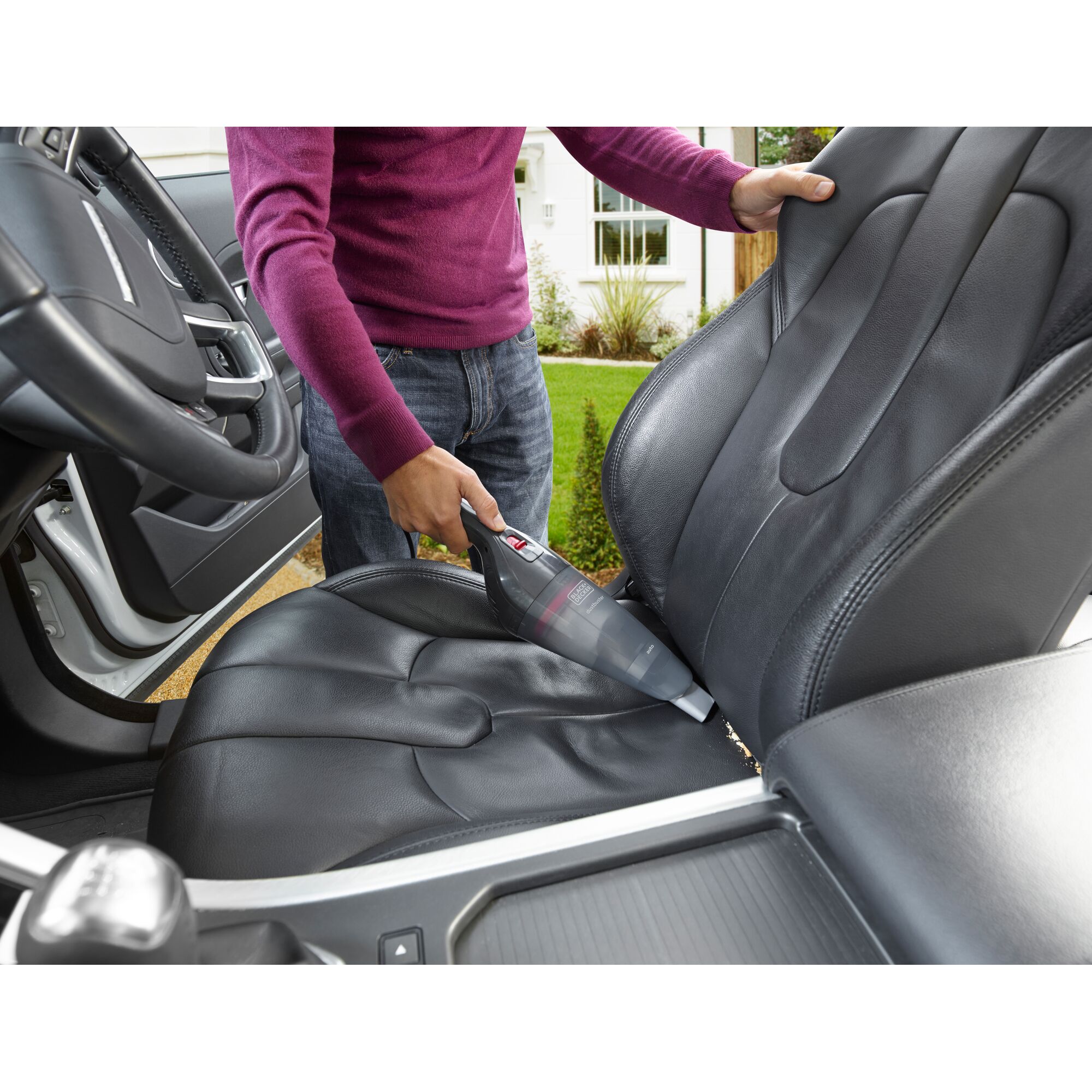 BLACKDECKER NVB12AVA handheld vacuum cleaning black car seat upholstery outdoors.