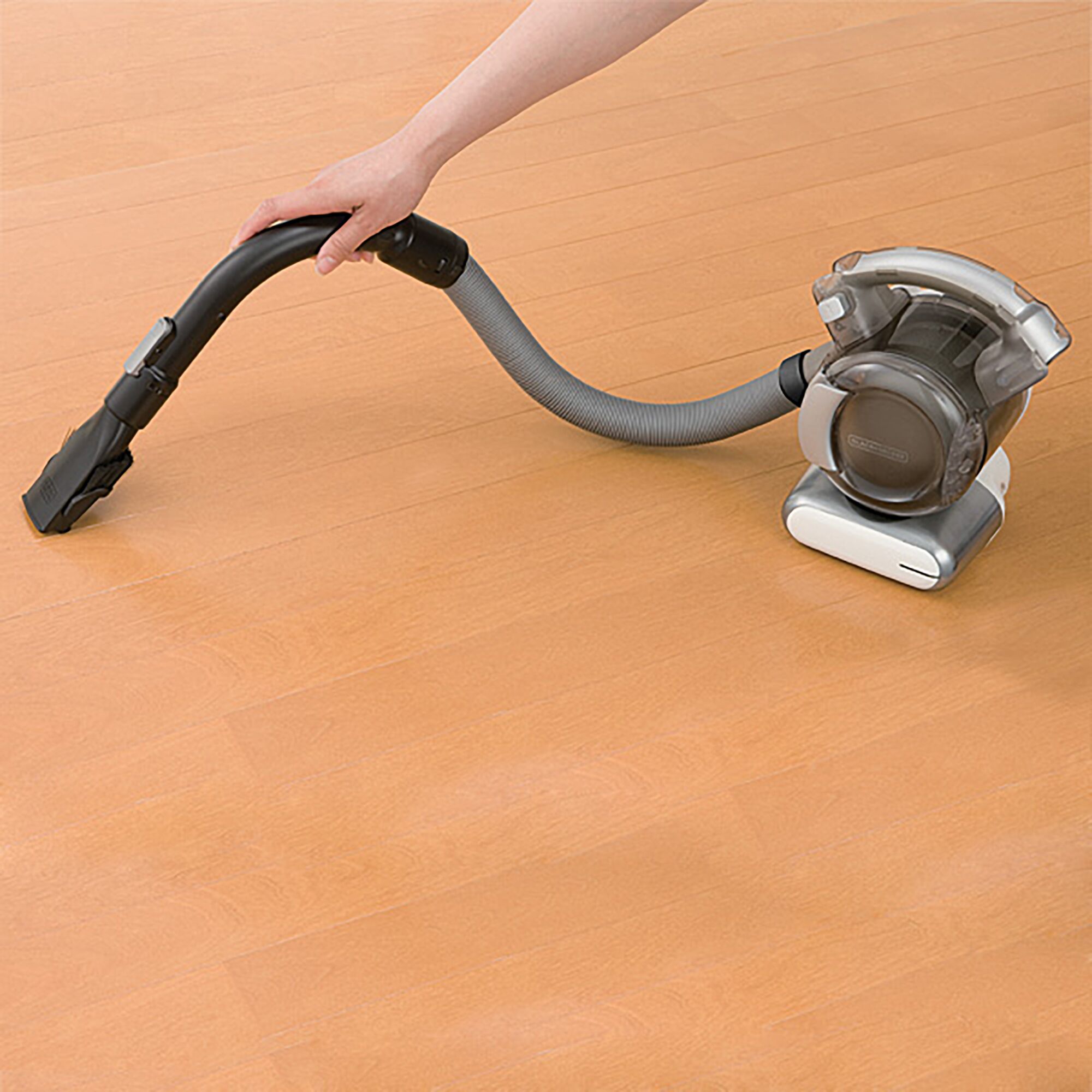BLACKDECKER PD1810LI handheld vacuum cleaner with hose on wooden floor, side angle.