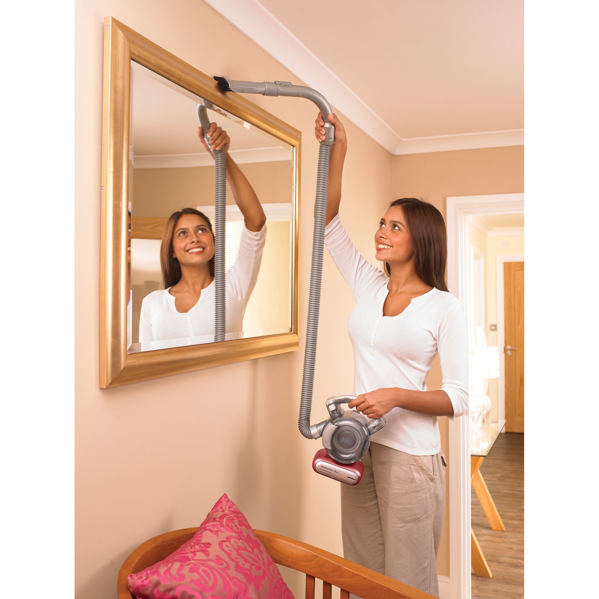 BLACKDECKER PD1810LR handheld vacuum with long hose cleaning a mirror frame in a living room.