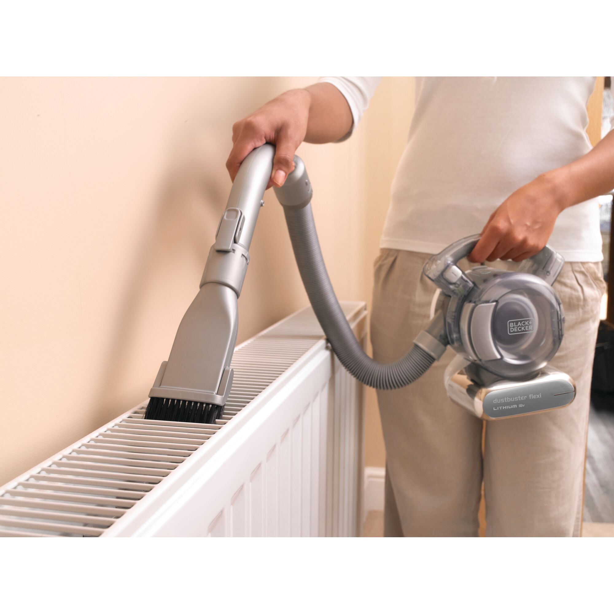 BLACK+DECKER PD1820LF handheld vacuum cleaner with flexible hose cleaning radiator, person holding device.