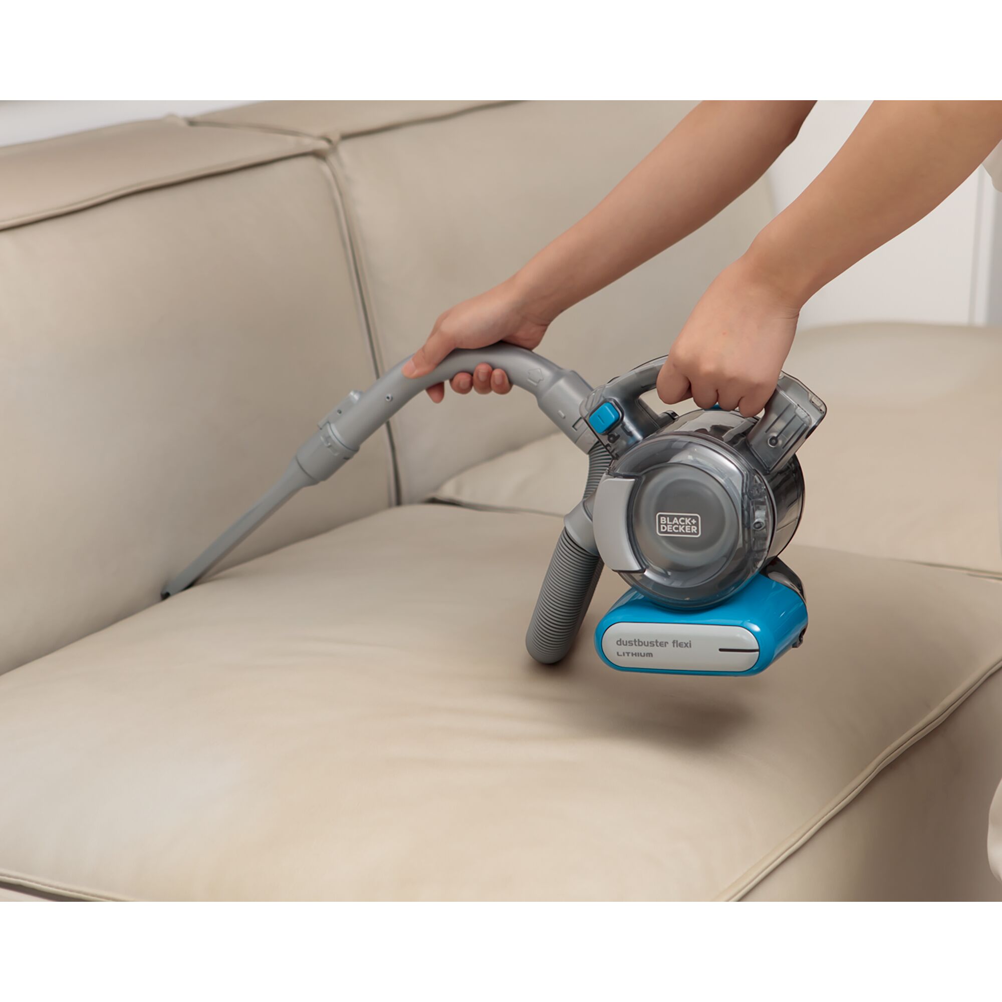BLACKDECKER PDB315JB handheld vacuum with hose cleaning a beige sofa cushion.