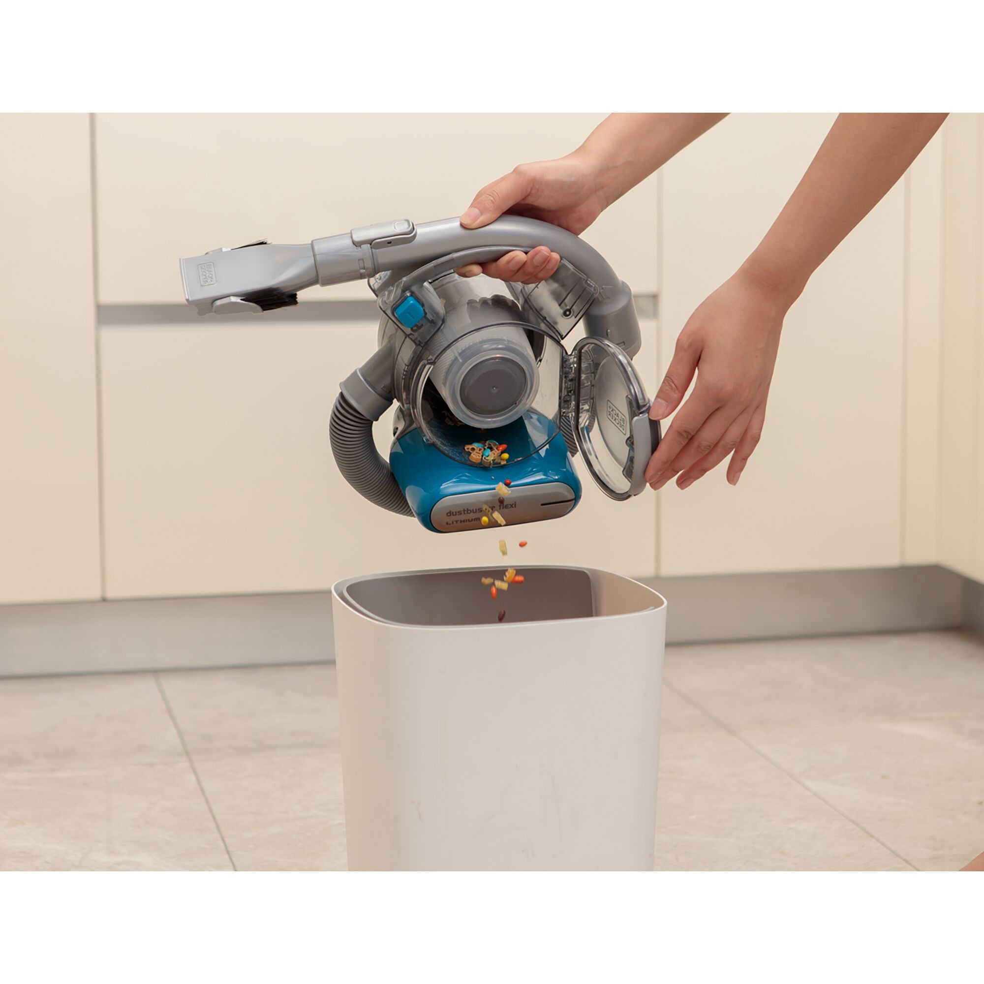 BLACKDECKER handheld vacuum PDB315JB being emptied into a trash bin in a kitchen setting.