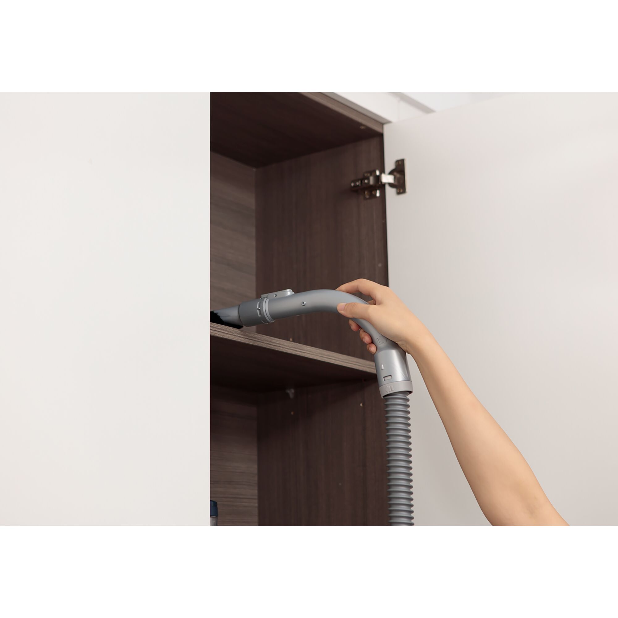 BLACKDECKER PDB315JB vacuum hose cleaning inside a wooden cabinet, close-up side view.