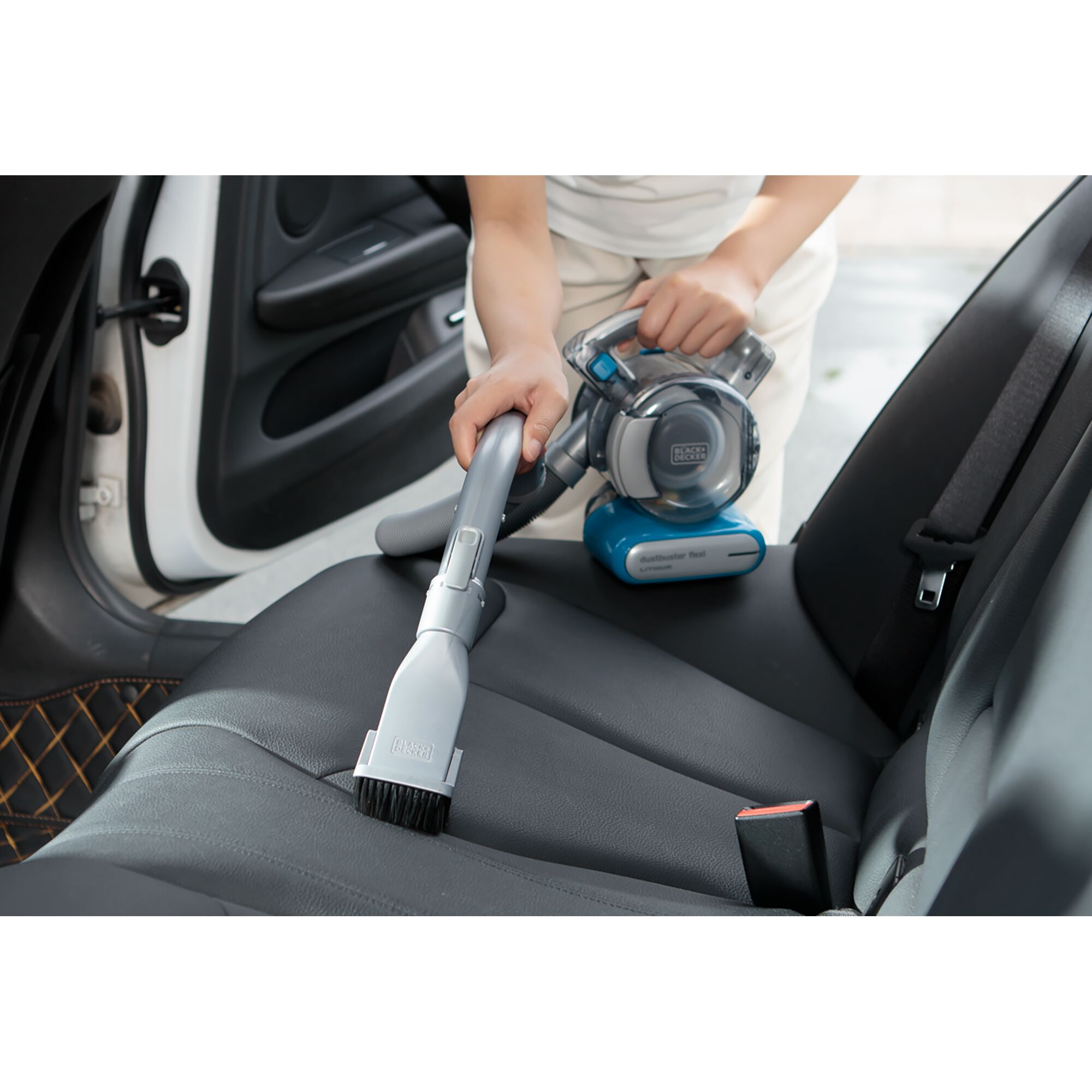 BLACK+DECKER PDB315JB handheld vacuum cleaning a car seat with brush attachment.