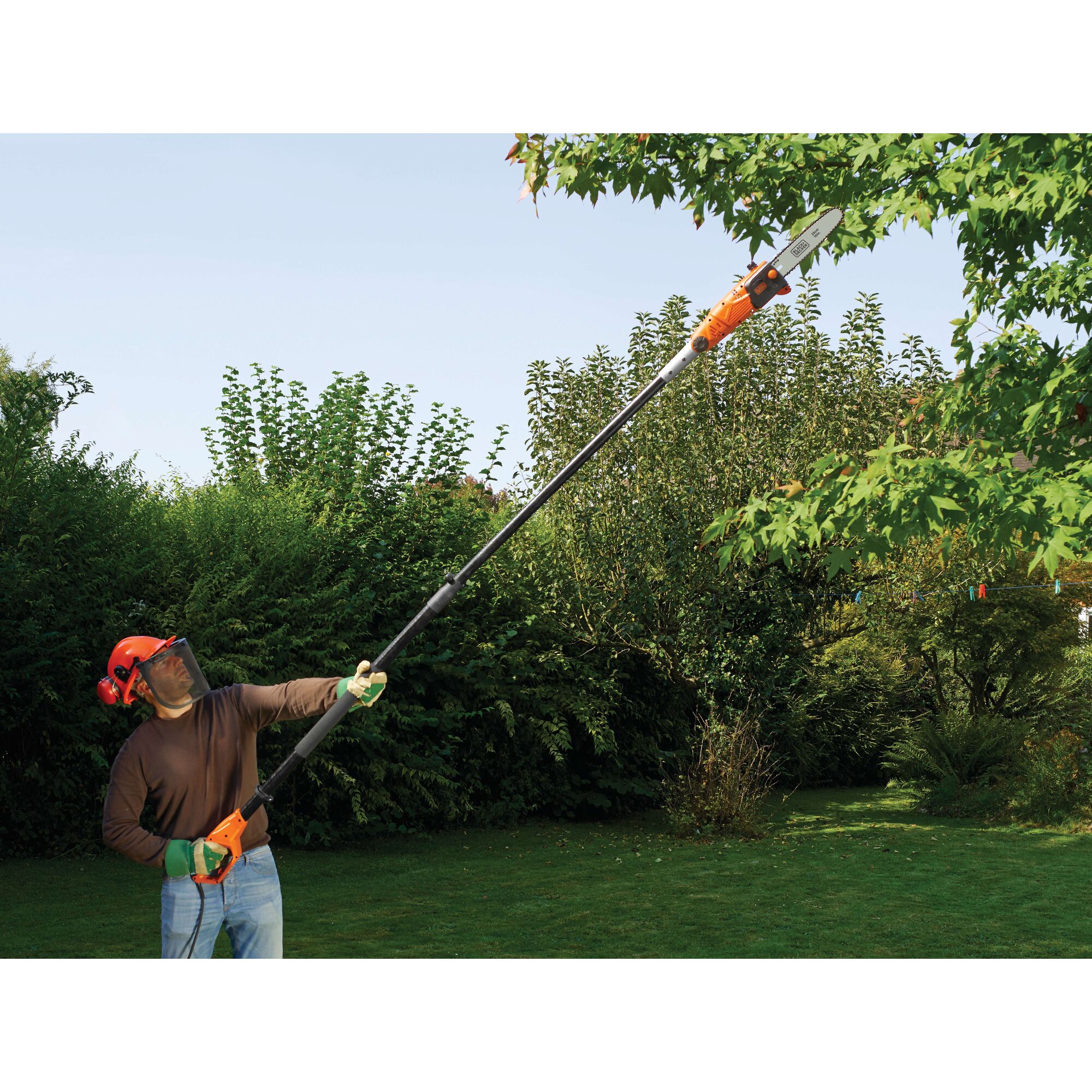 BLACKDECKER PS7525 pole saw used for trimming tree branches outdoors in a garden setting.