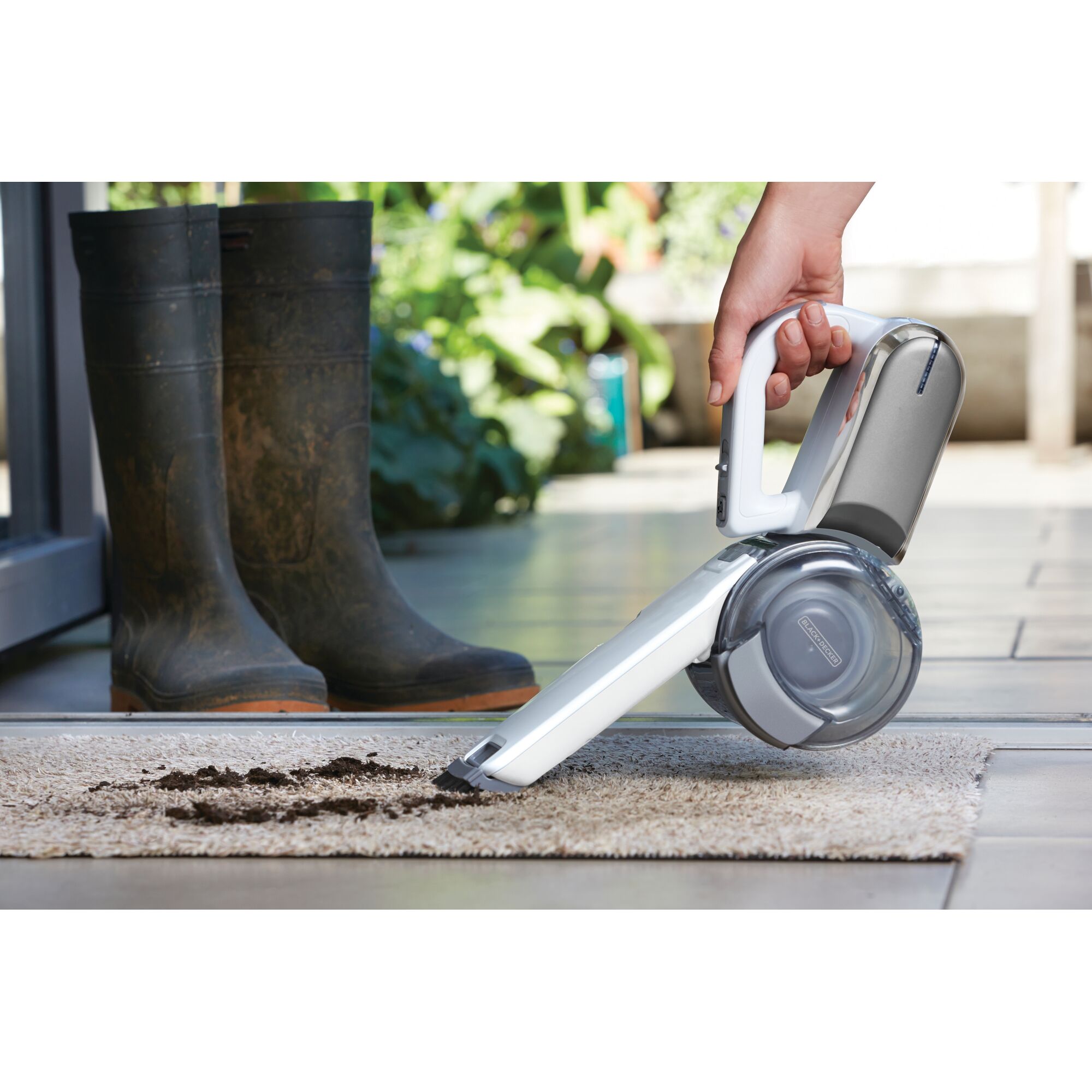 BLACKDECKER PV1020CAC handheld vacuum cleaning dirt from carpet near boots, side view.