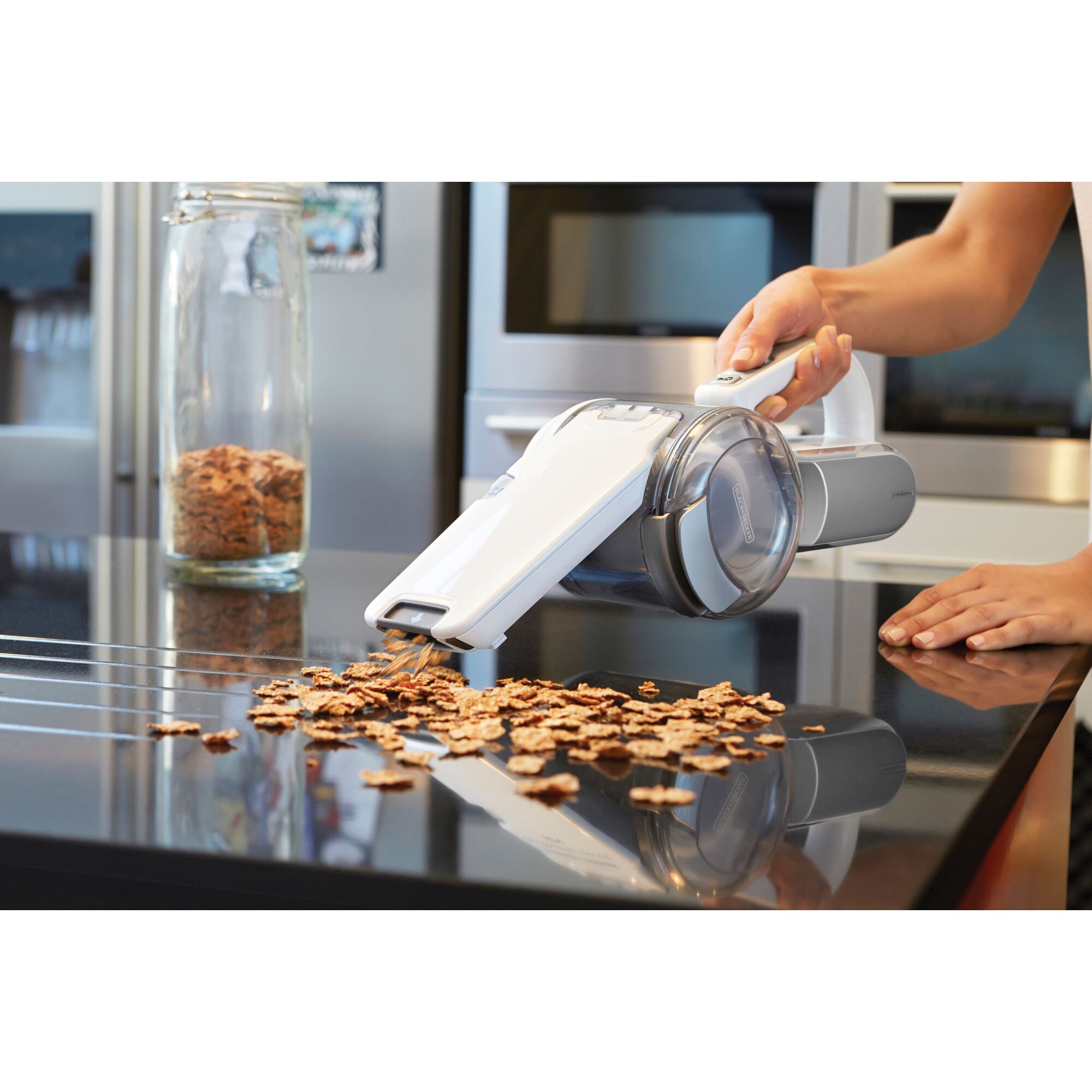 BLACKDECKER PV1020CAC handheld vacuum cleaning cereal from kitchen counter, angled side view.