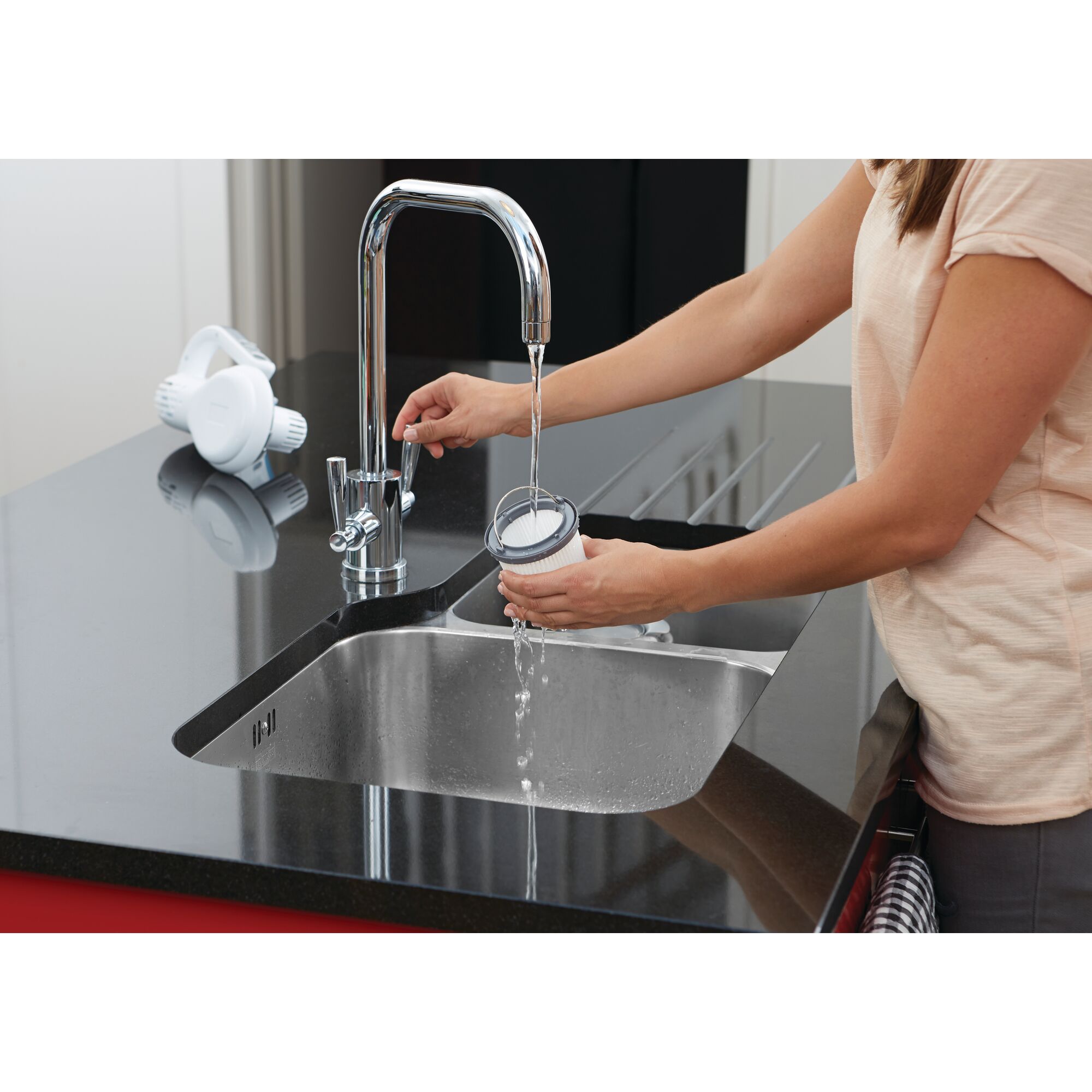 BLACKDECKER PV1020CAC filter being rinsed under kitchen faucet in a modern sink.