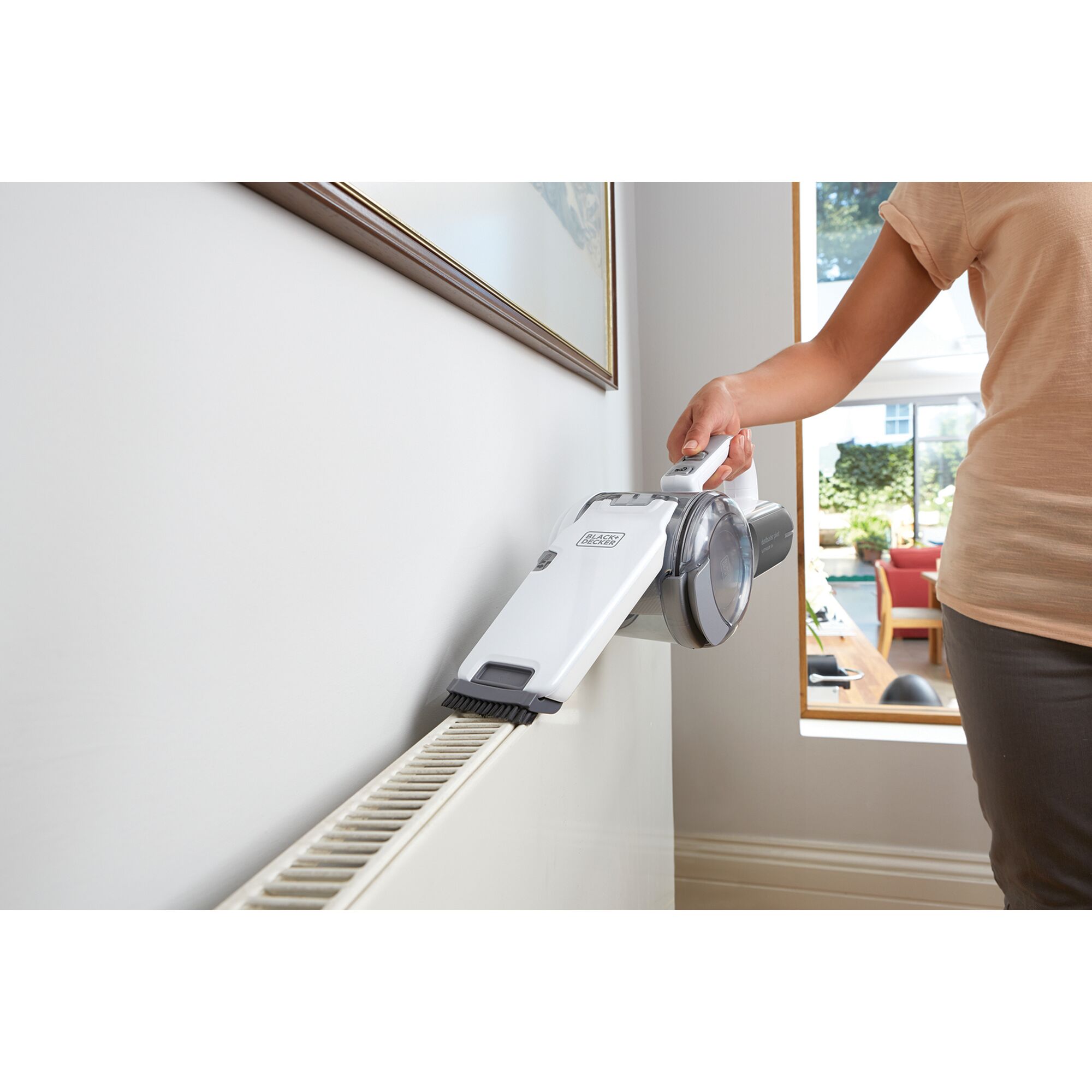 BLACKDECKER PV1820LF handheld vacuum cleaning a radiator in a home setting.