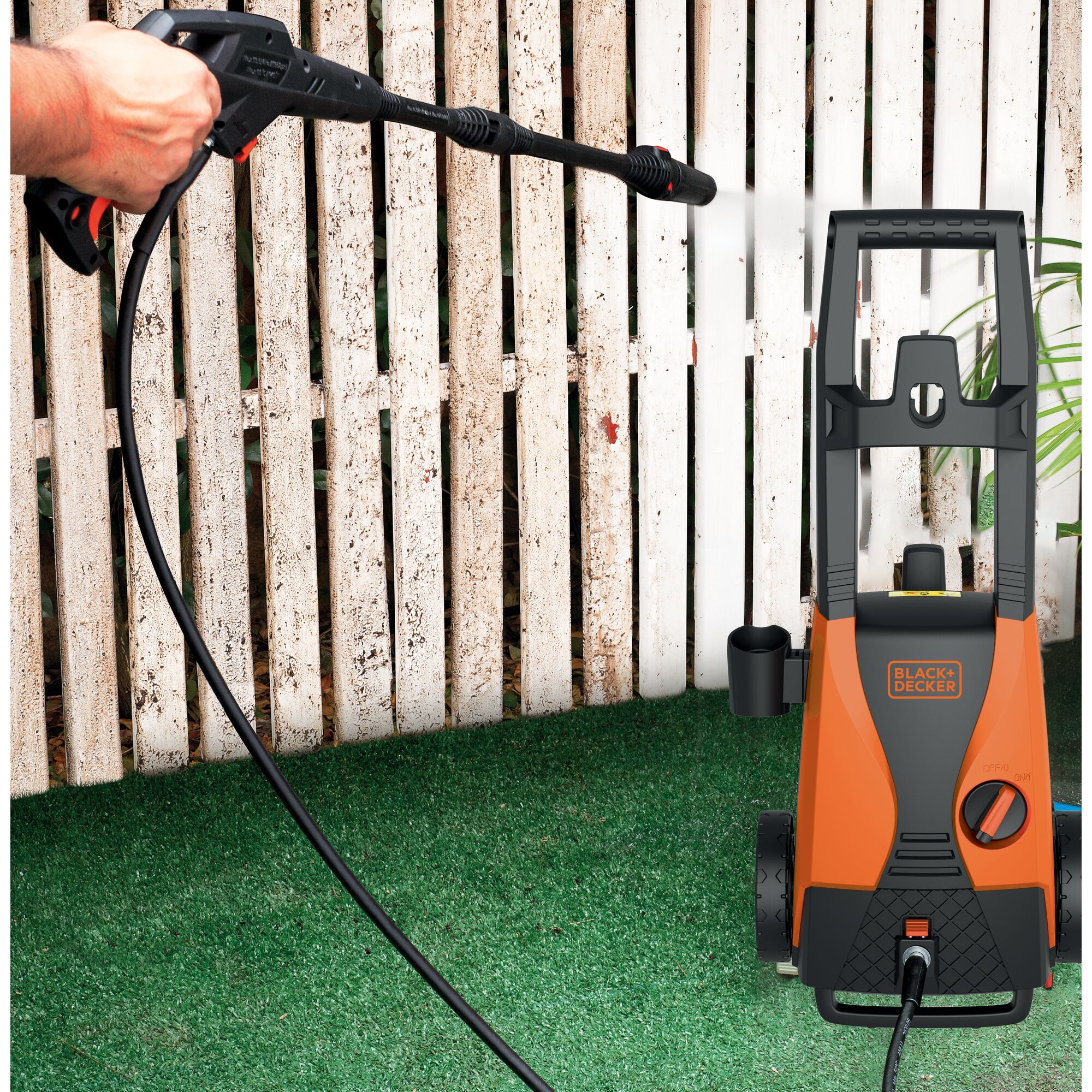 BLACKDECKER PW1450TDL pressure washer cleaning a white fence outdoors.