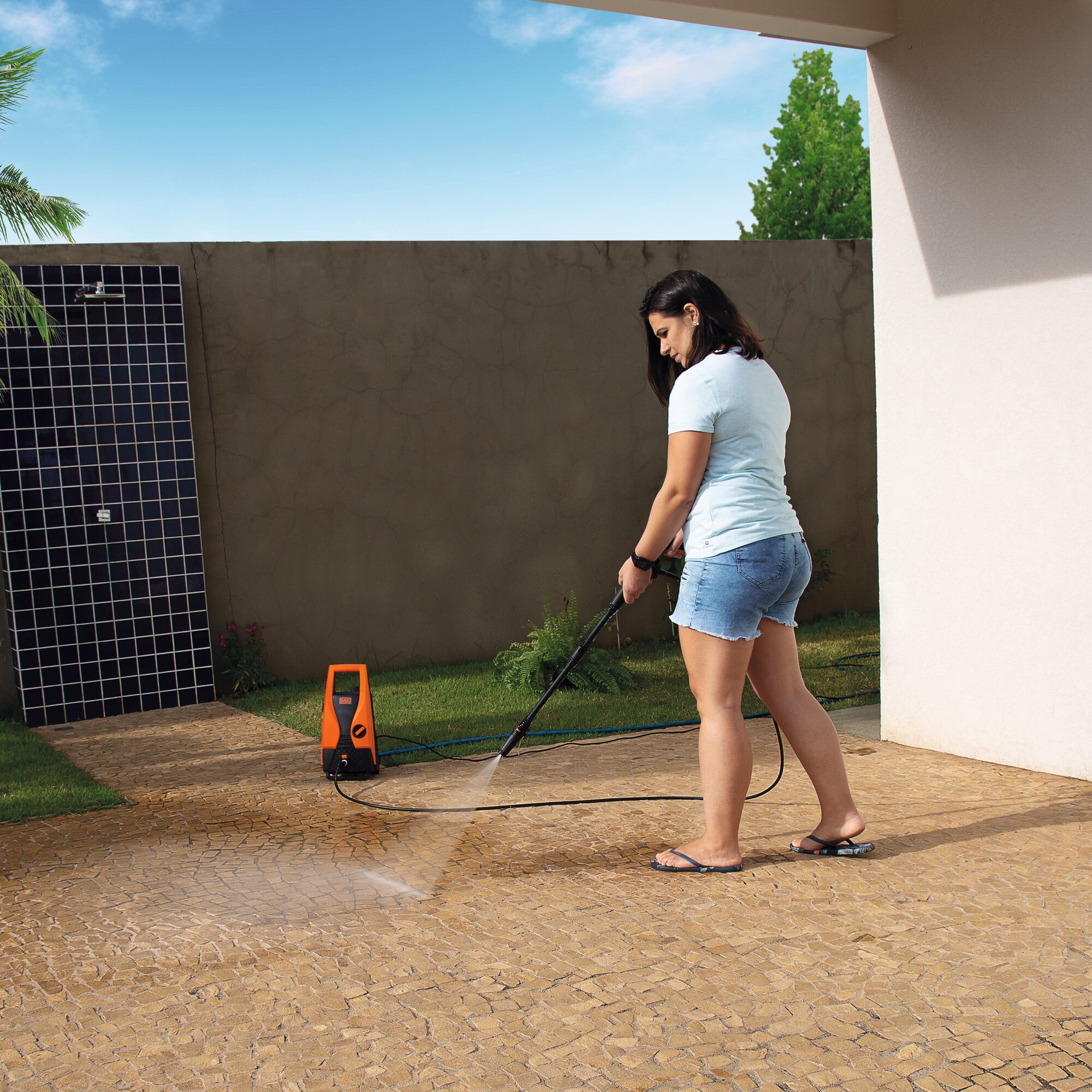BLACKDECKER PW1450TD pressure washer cleaning patio tiles outdoors.