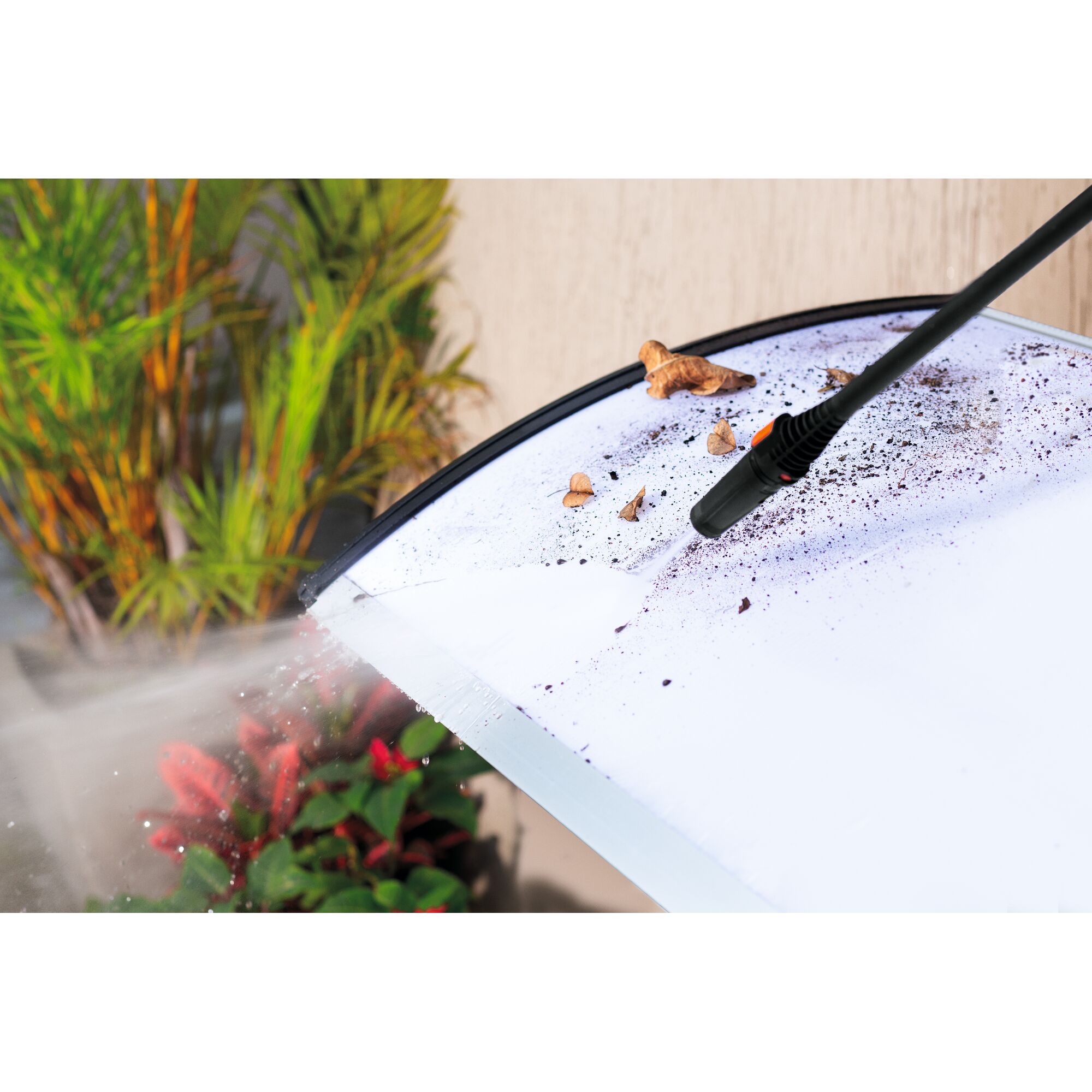 BLACKDECKER PW1450TD pressure washer cleaning dirty surface with water spray, plants in background.