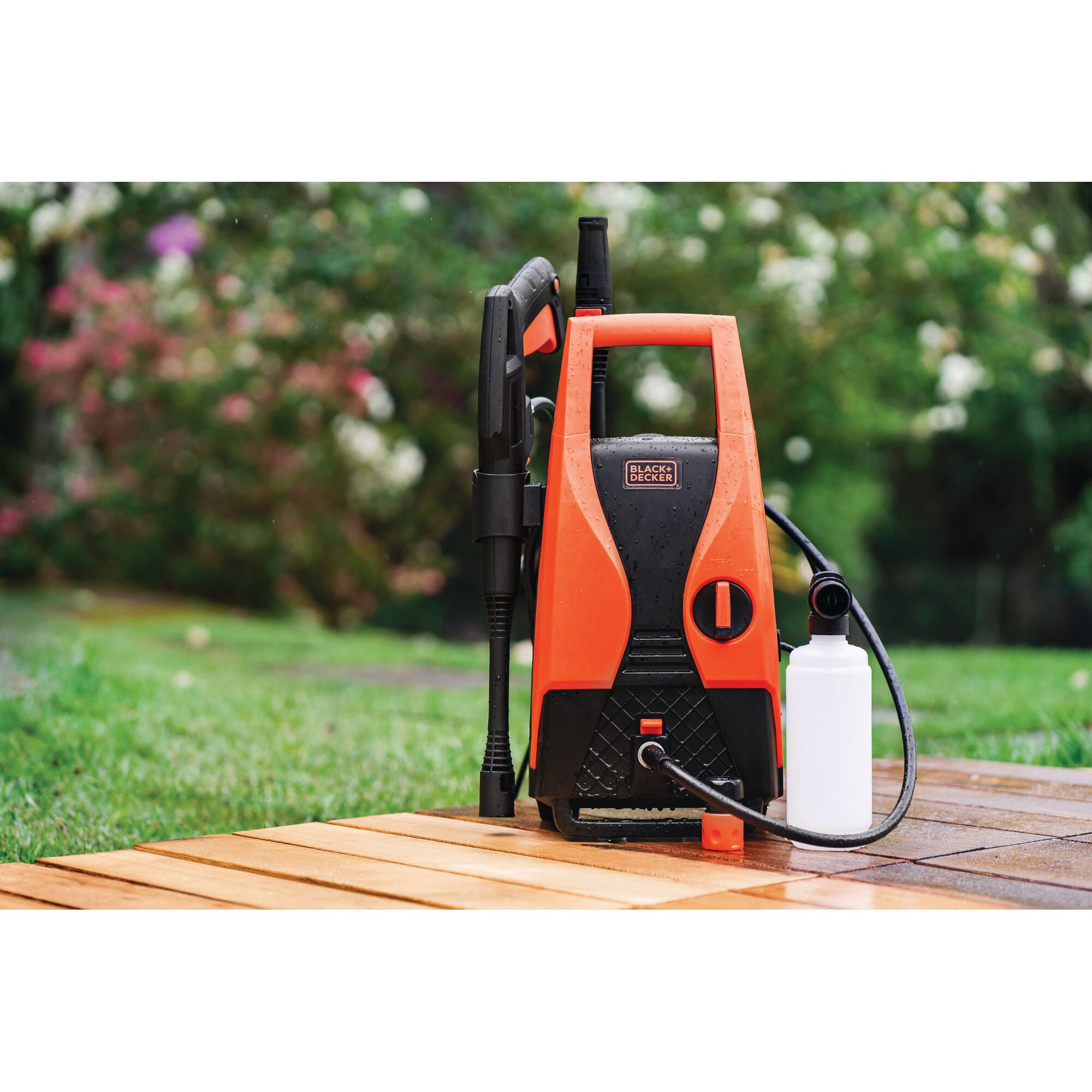 BLACKDECKER PW1450TD pressure washer in orange and black with accessories on outdoor patio.