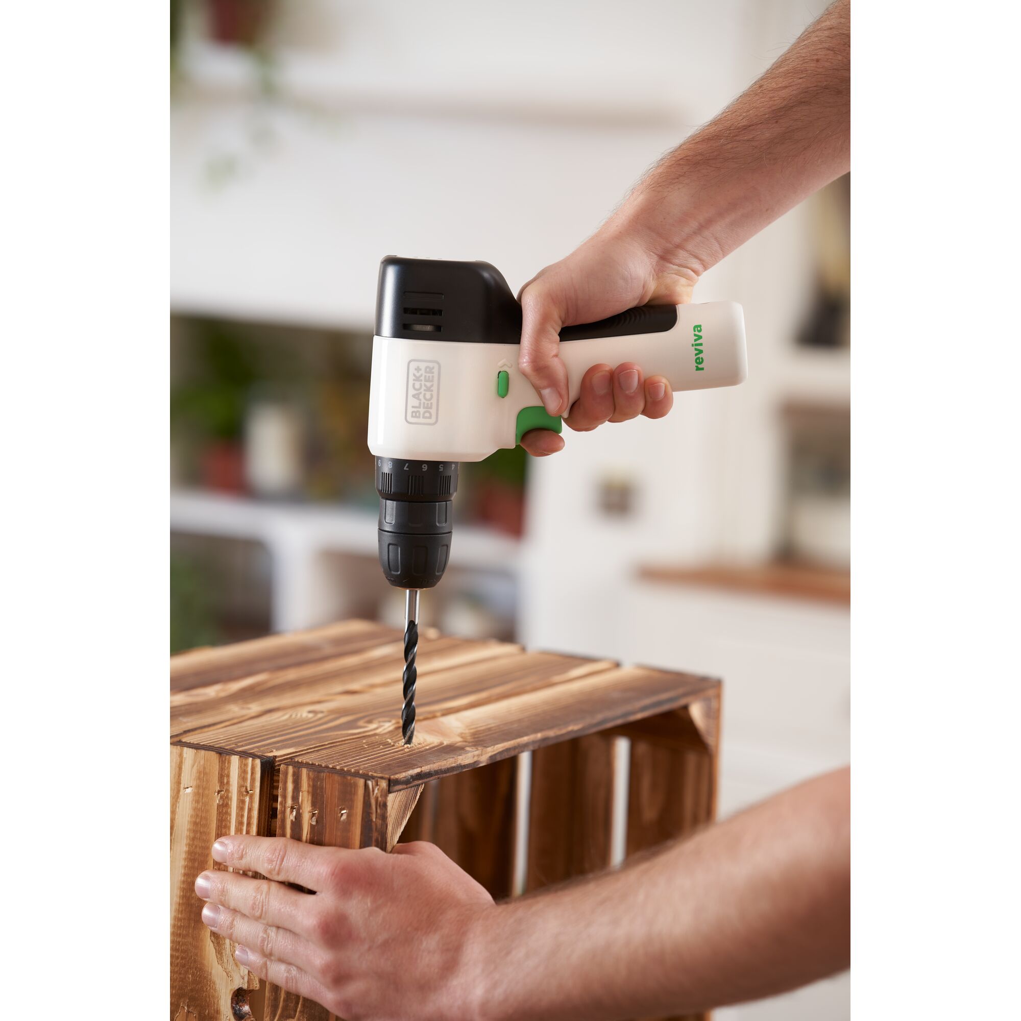 Photo of BLACK+DECKER REVDD12C cordless drill being used to drill into a wooden crate indoors.