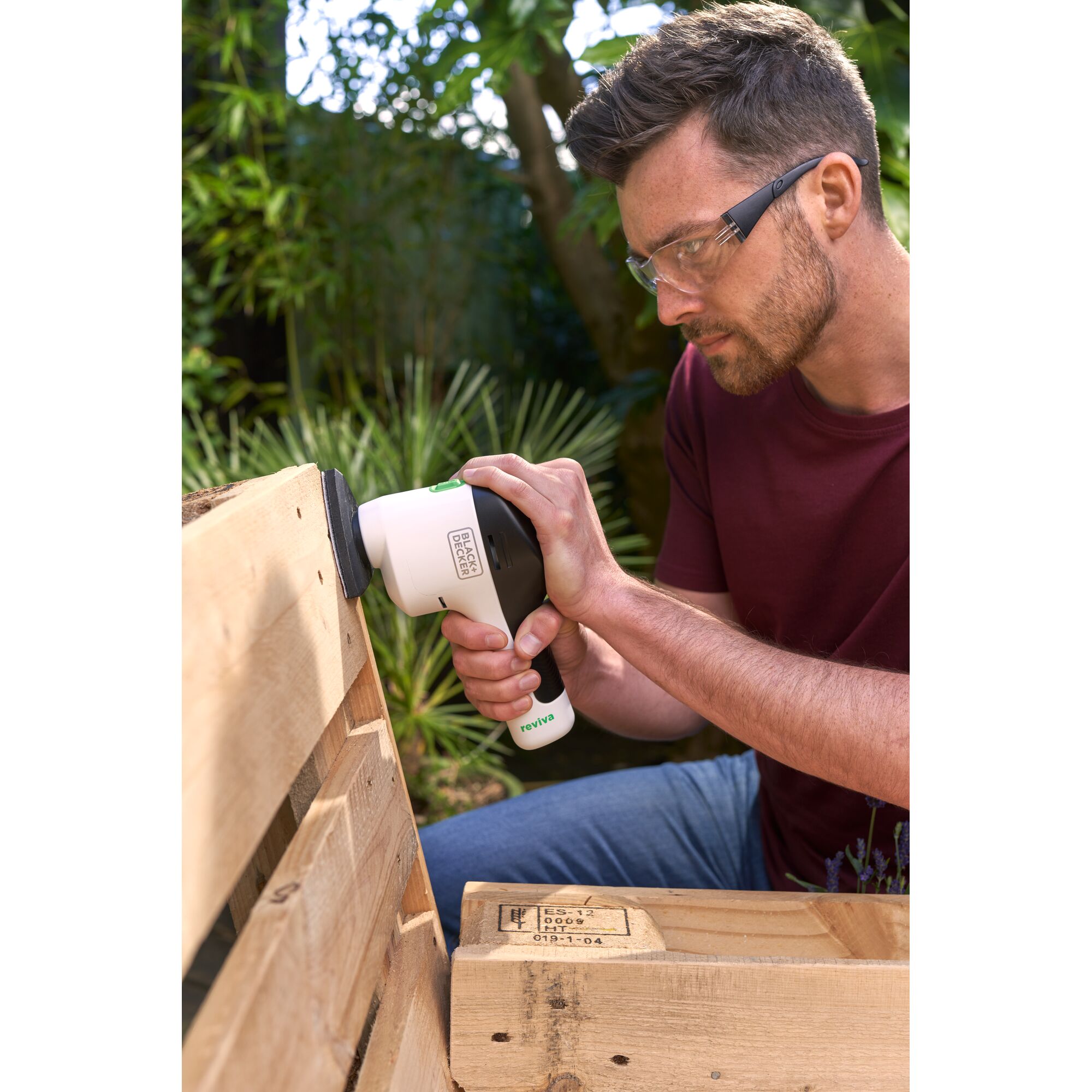 BLACK+DECKER REVDS12C sander being used on a wooden pallet outdoors.