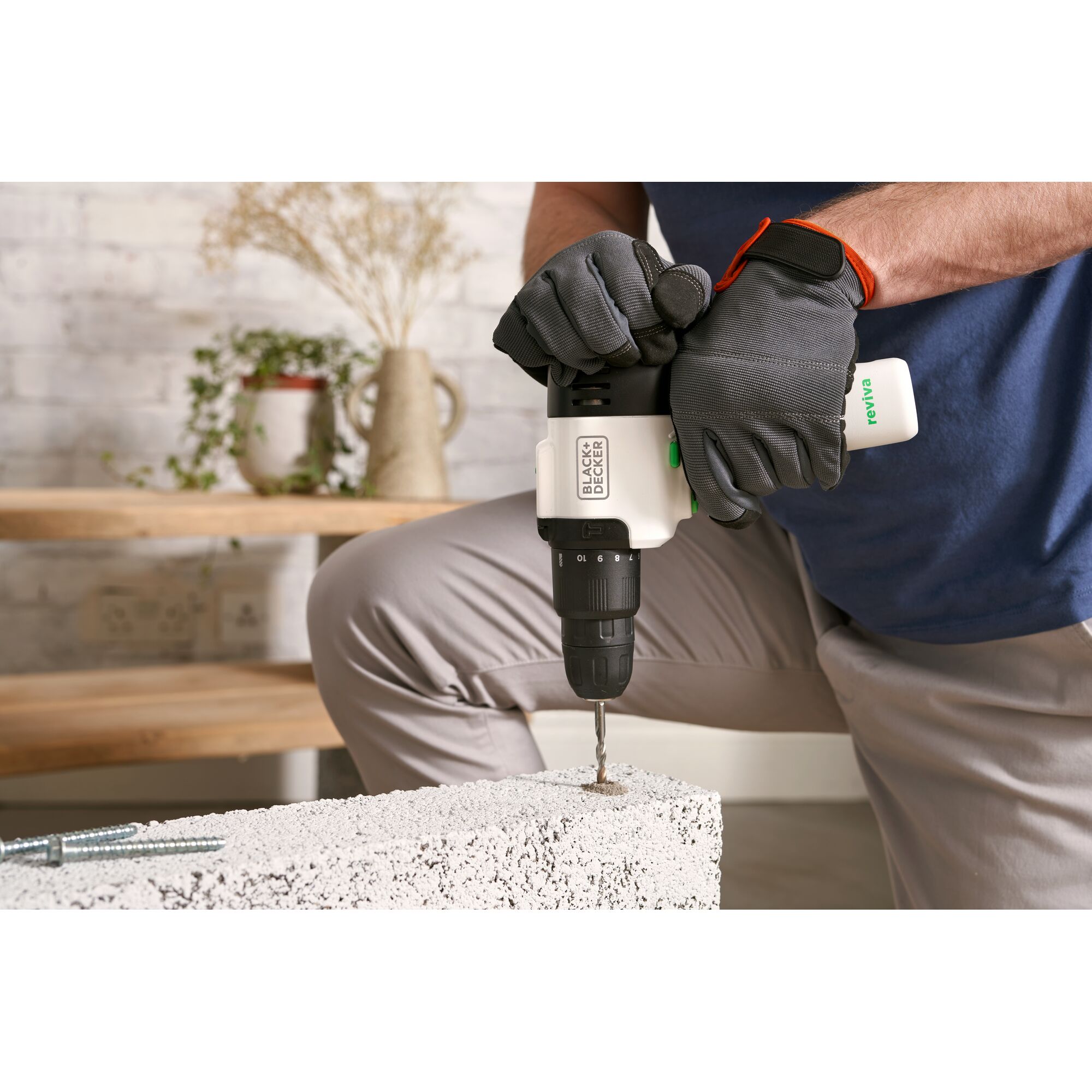 Photo of BLACKDECKER REVHD12C cordless drill in use with gloved hands drilling into concrete indoors.