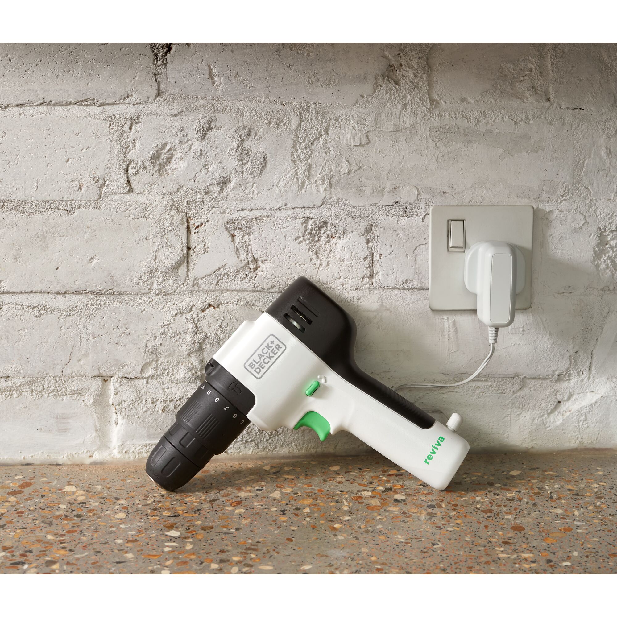 BLACKDECKER REVHD12C cordless drill with black and white body charging on countertop by white brick wall.