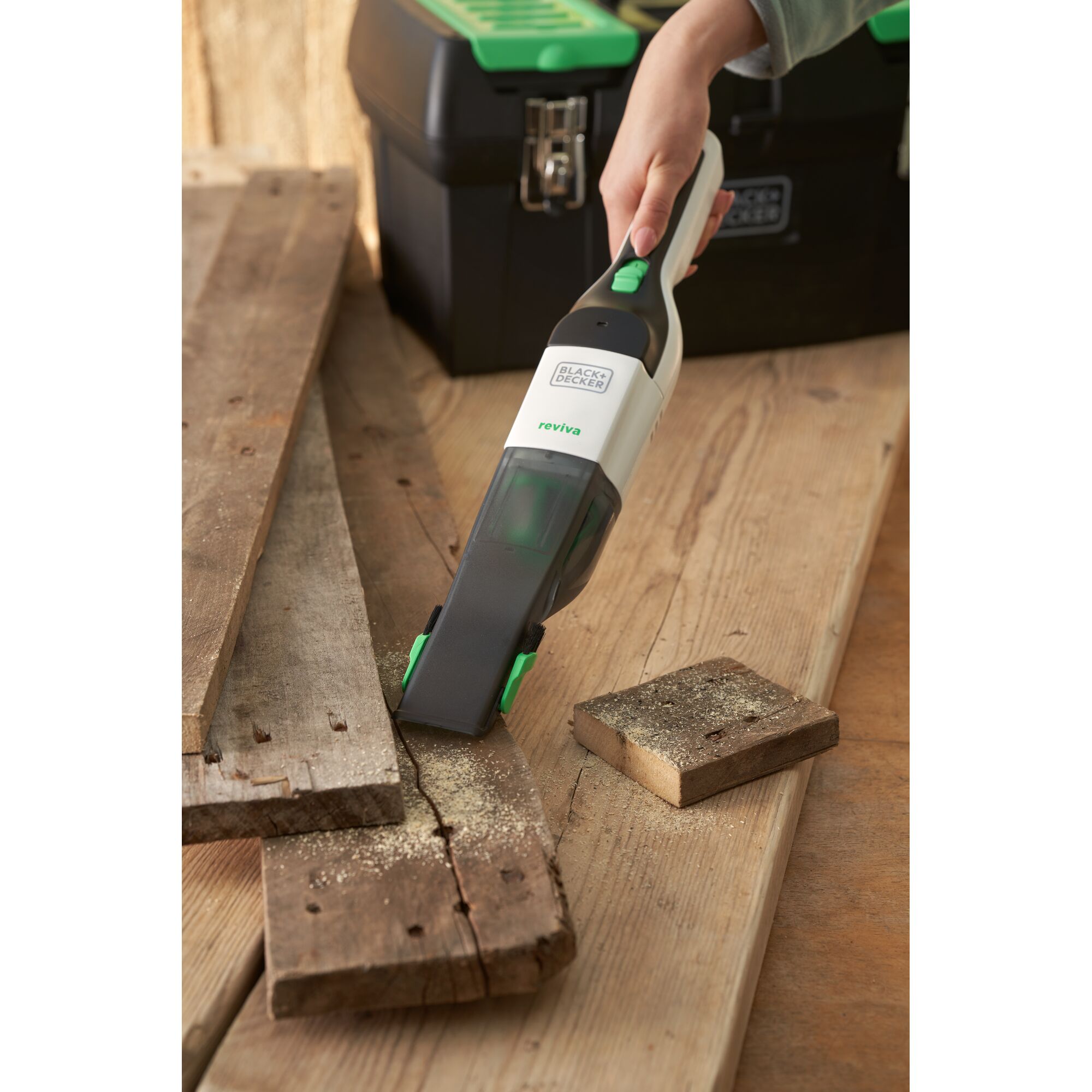 BLACKDECKER REVHV8C handheld vacuum cleaning sawdust on wood near toolbox, product in use.