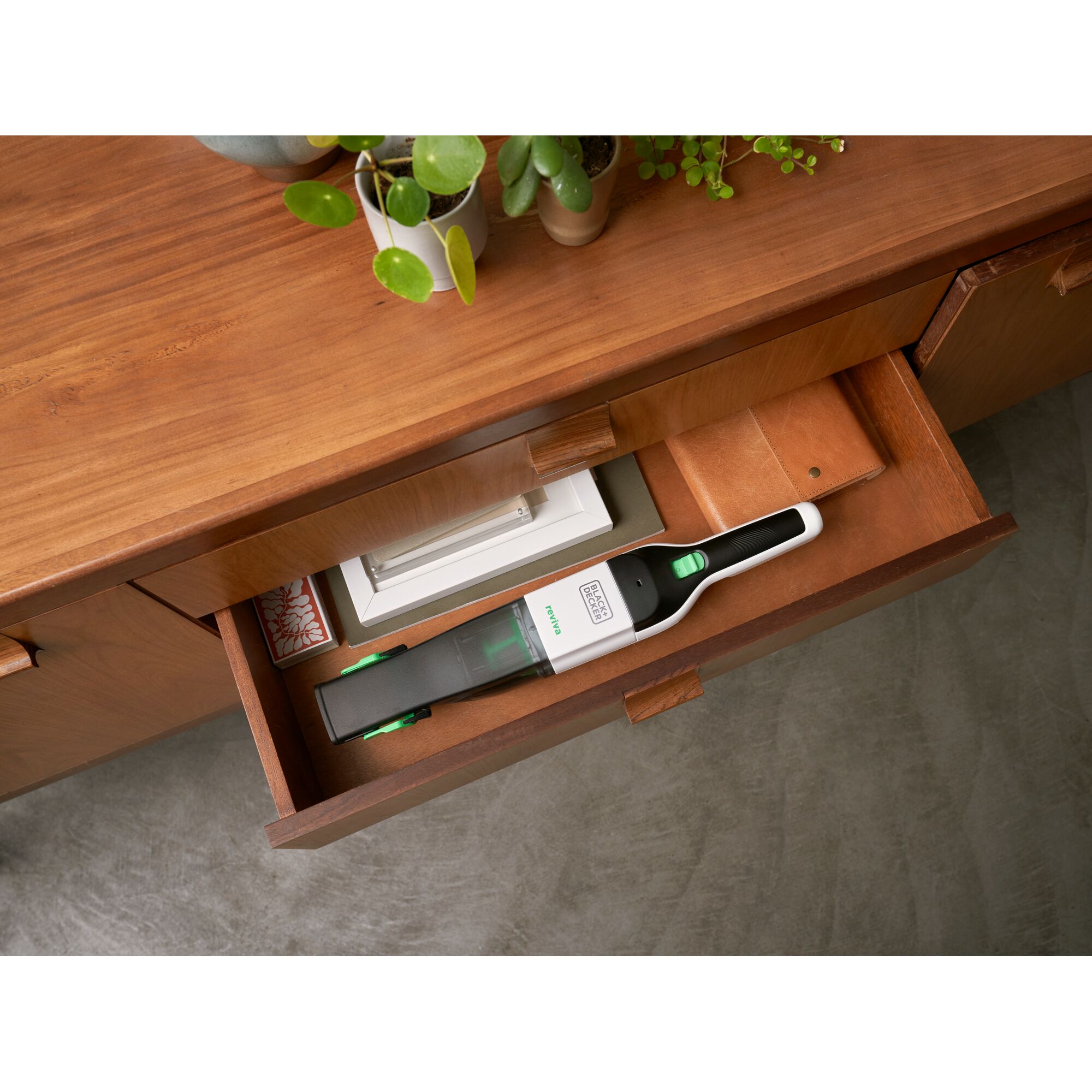 BLACK+DECKER REVHV8C handheld vacuum cleaner stored in a wooden drawer, white and black design with green accents.