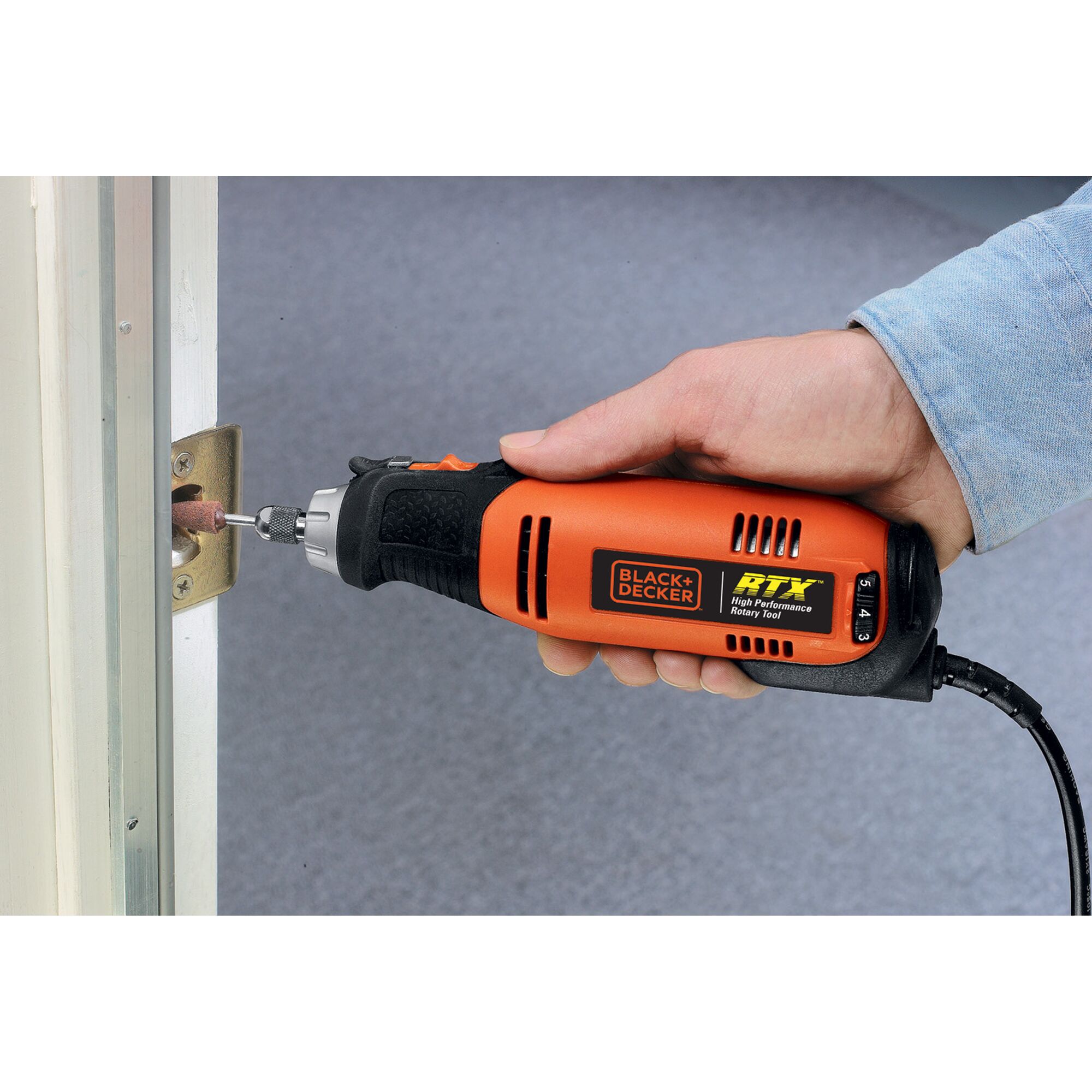 BLACK+DECKER RTX1 rotary tool in use sanding metal door plate, close-up view.