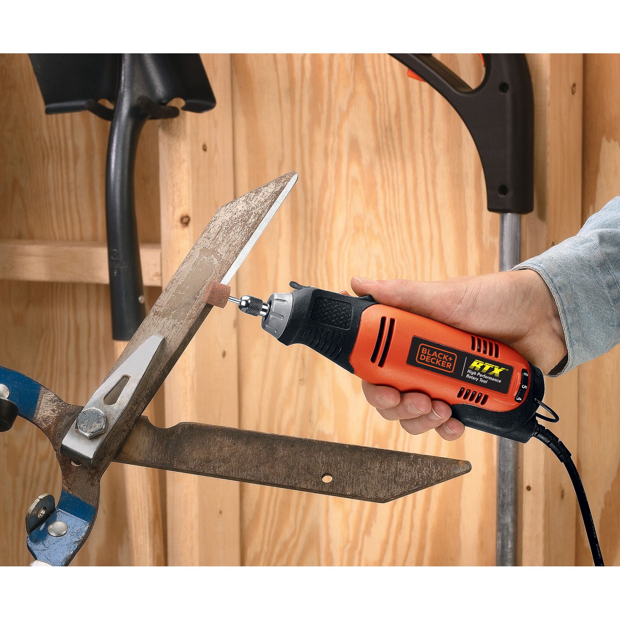 BLACK+DECKER RTX1 rotary tool sharpening a metal blade, close-up of tool in hand, orange and black design.