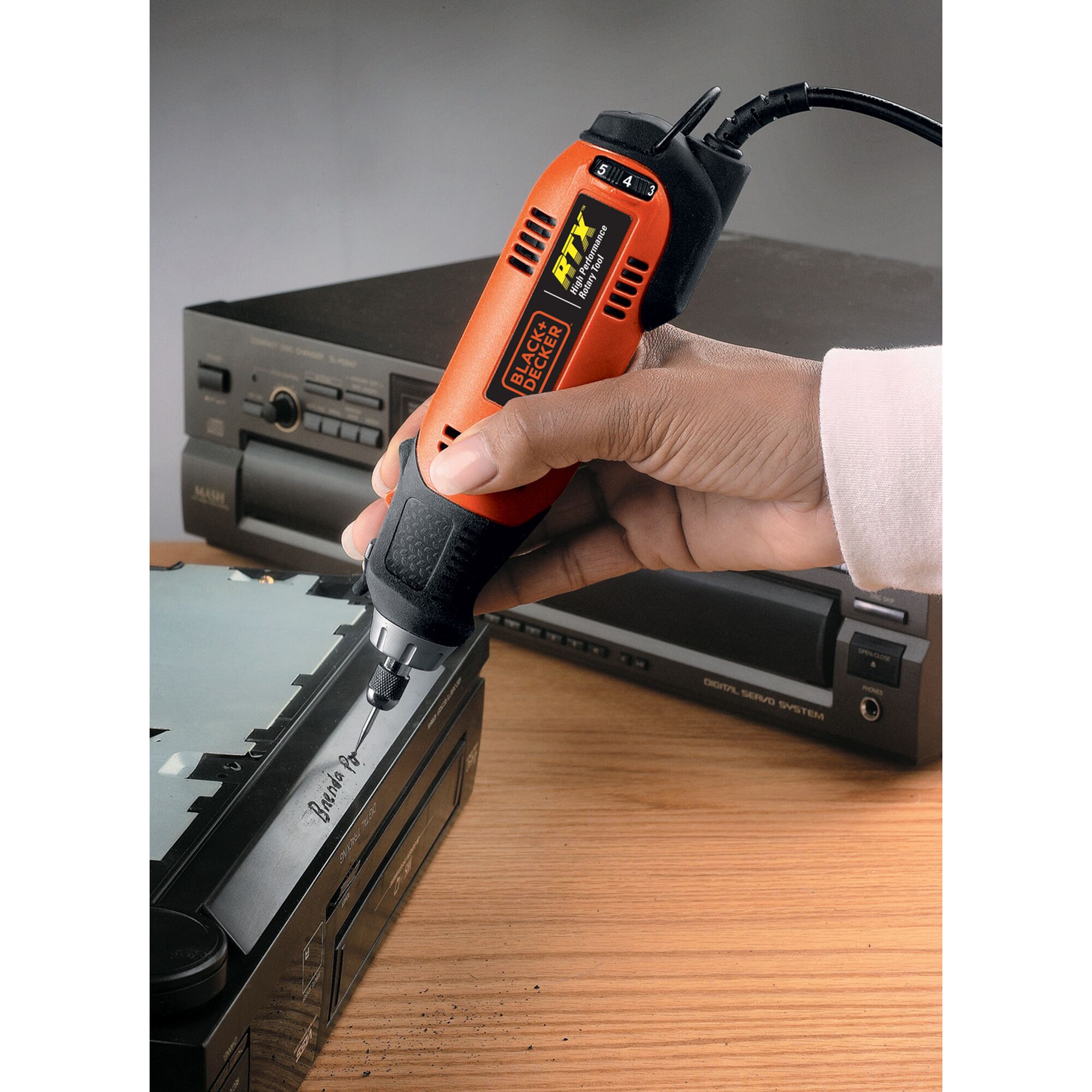 BLACKDECKER RTX1 rotary tool used for engraving on electronic device, handheld close-up.