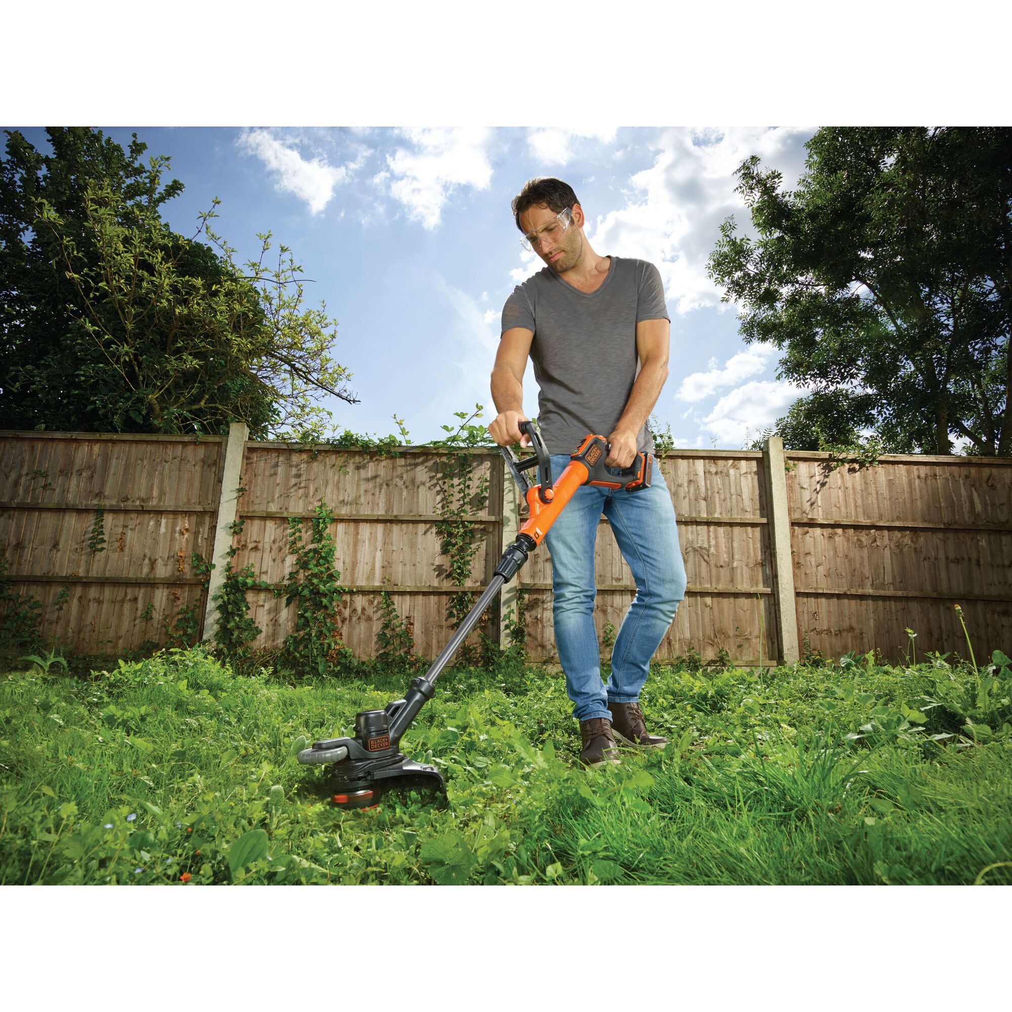 BLACKDECKER STC1820EPCF cordless grass trimmer in use outdoors by a person on lawn.