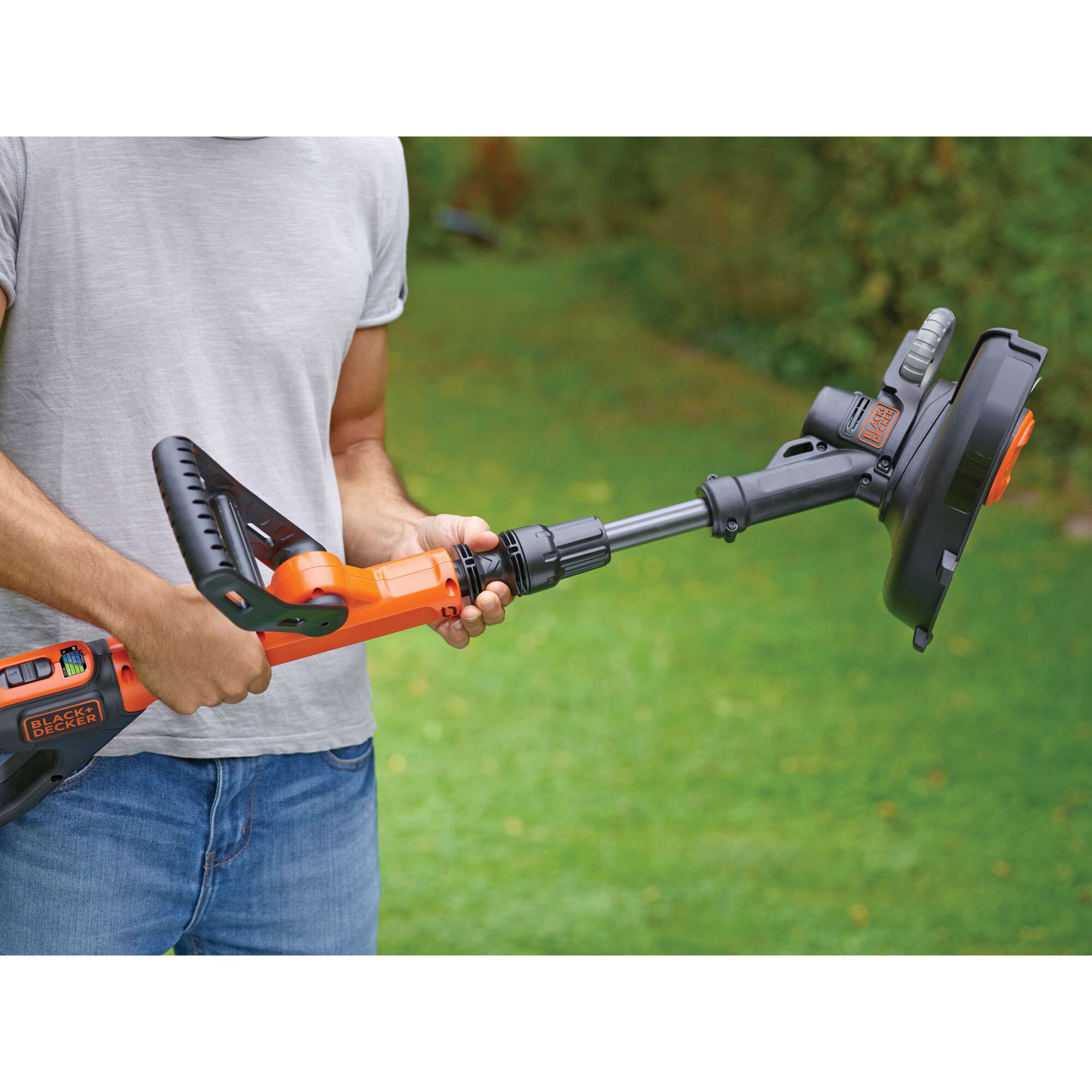 Photo of BLACKDECKER STC1820EPC grass trimmer held by person outdoors, orange and black design.