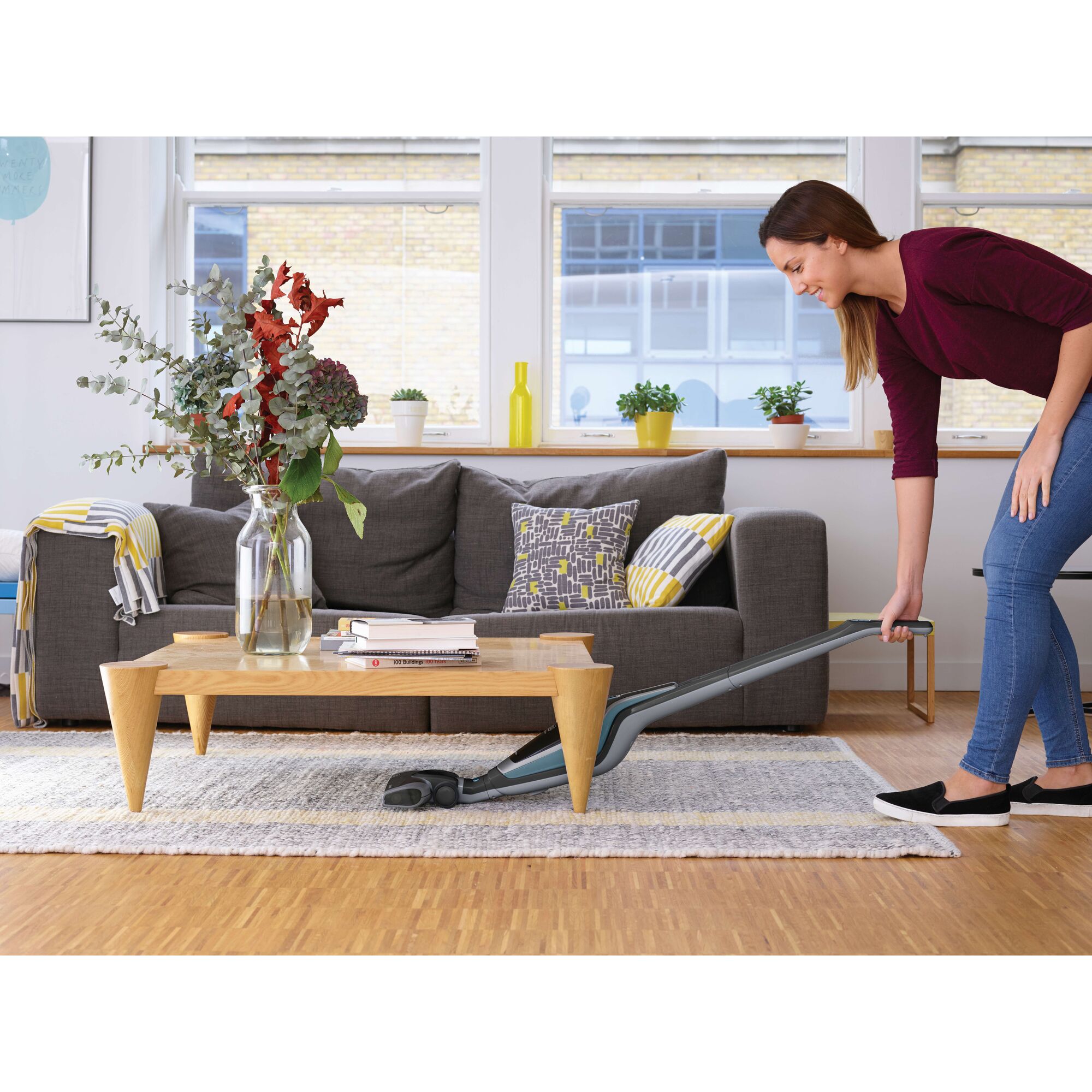 BLACKDECKER SVA420B vacuum cleaner being used under a coffee table in a modern living room.