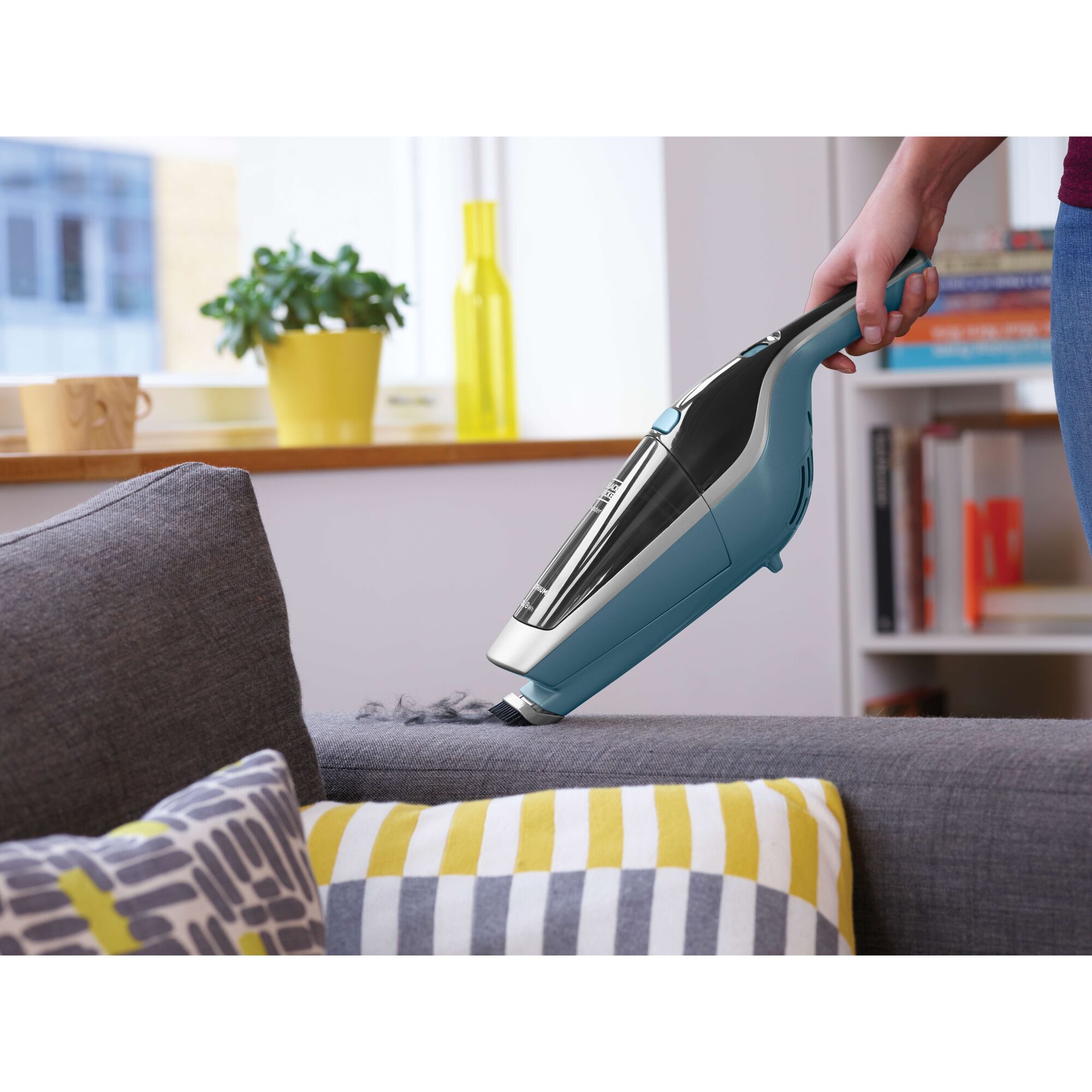 BLACKDECKER SVA420B handheld vacuum cleaning a gray sofa in a modern living room setting.