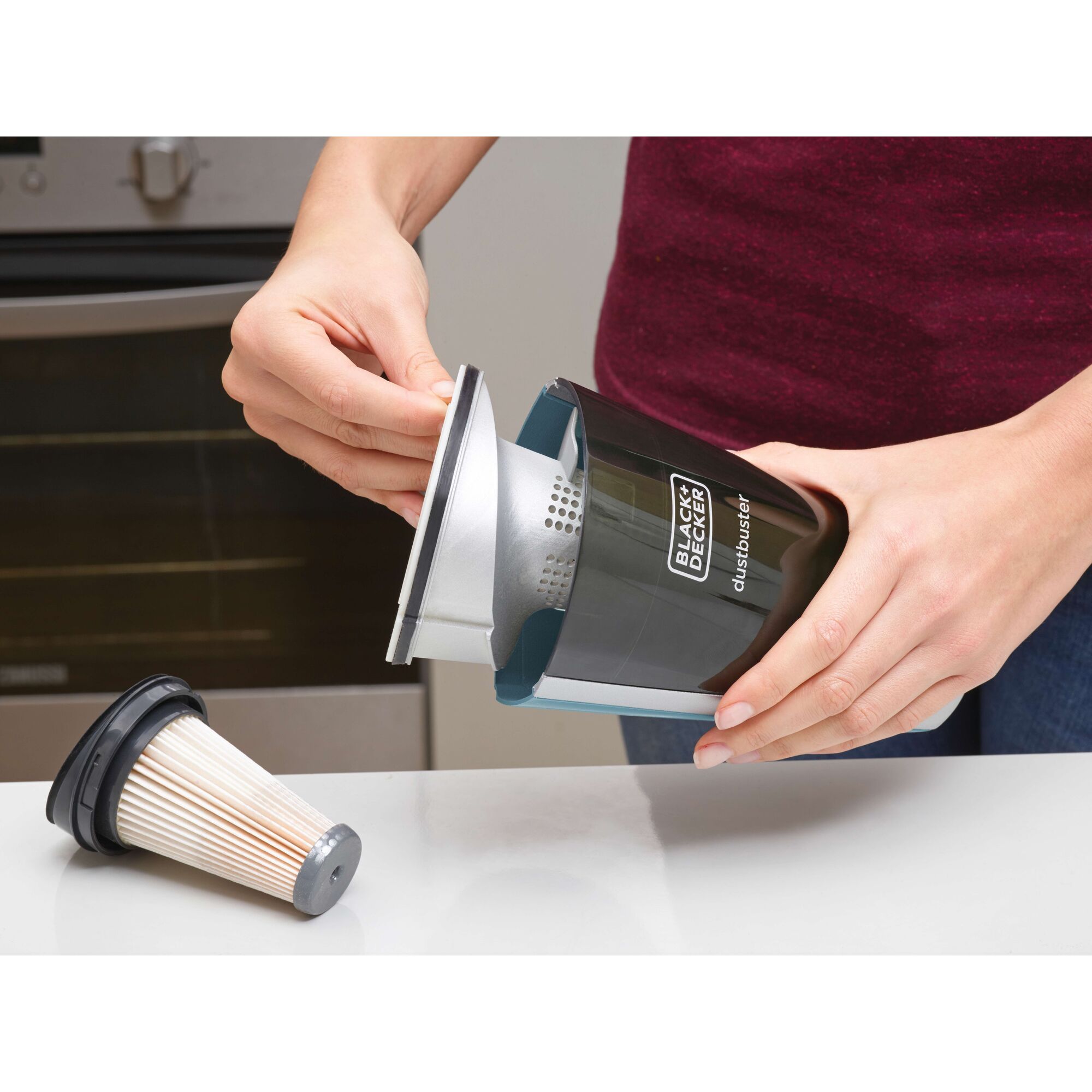 BLACKDECKER SVA420B dustbuster filter being removed and cleaned on a kitchen counter, shown close-up.