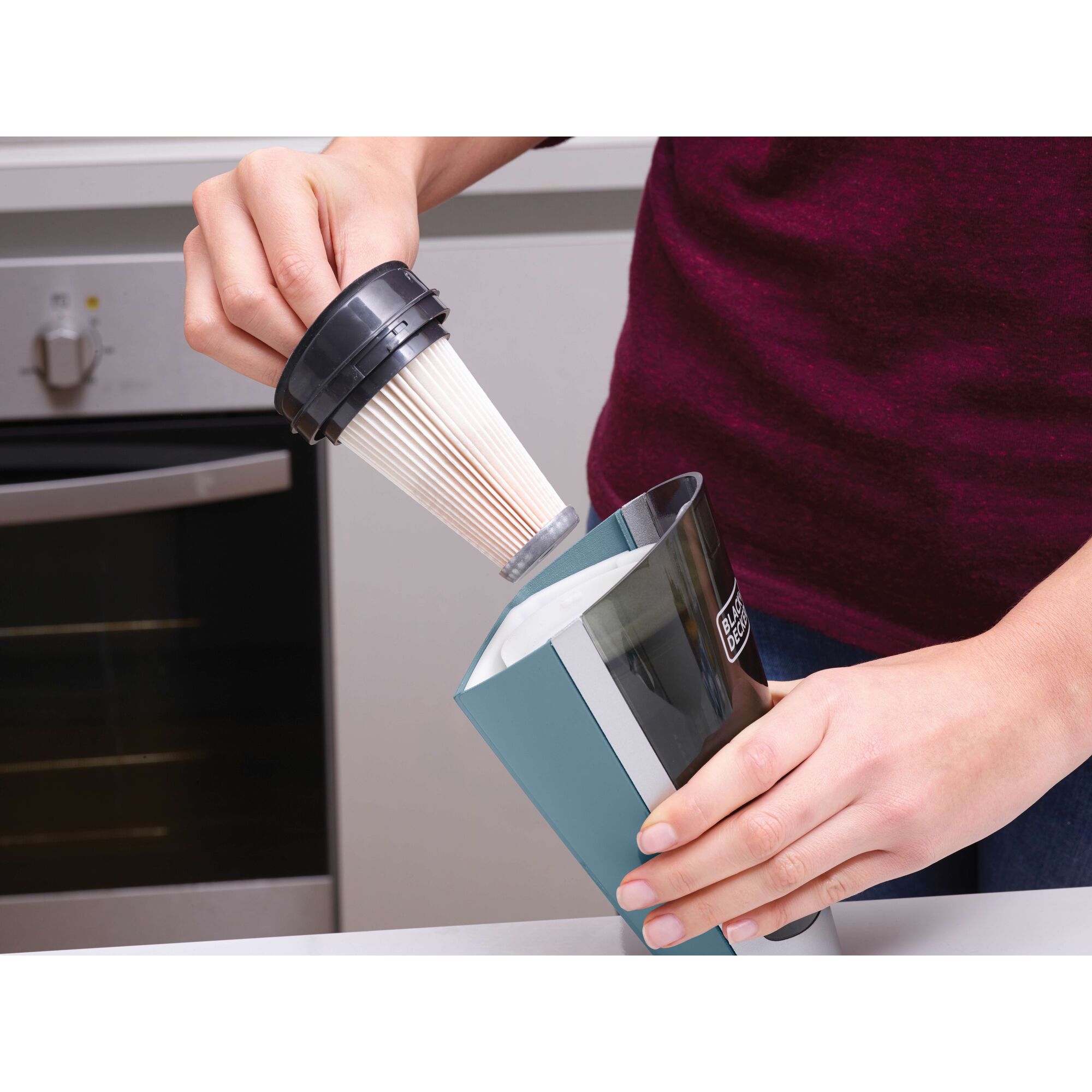 Photo of BLACKDECKER SVA420B vacuum filter being removed from dust container in a kitchen setting.