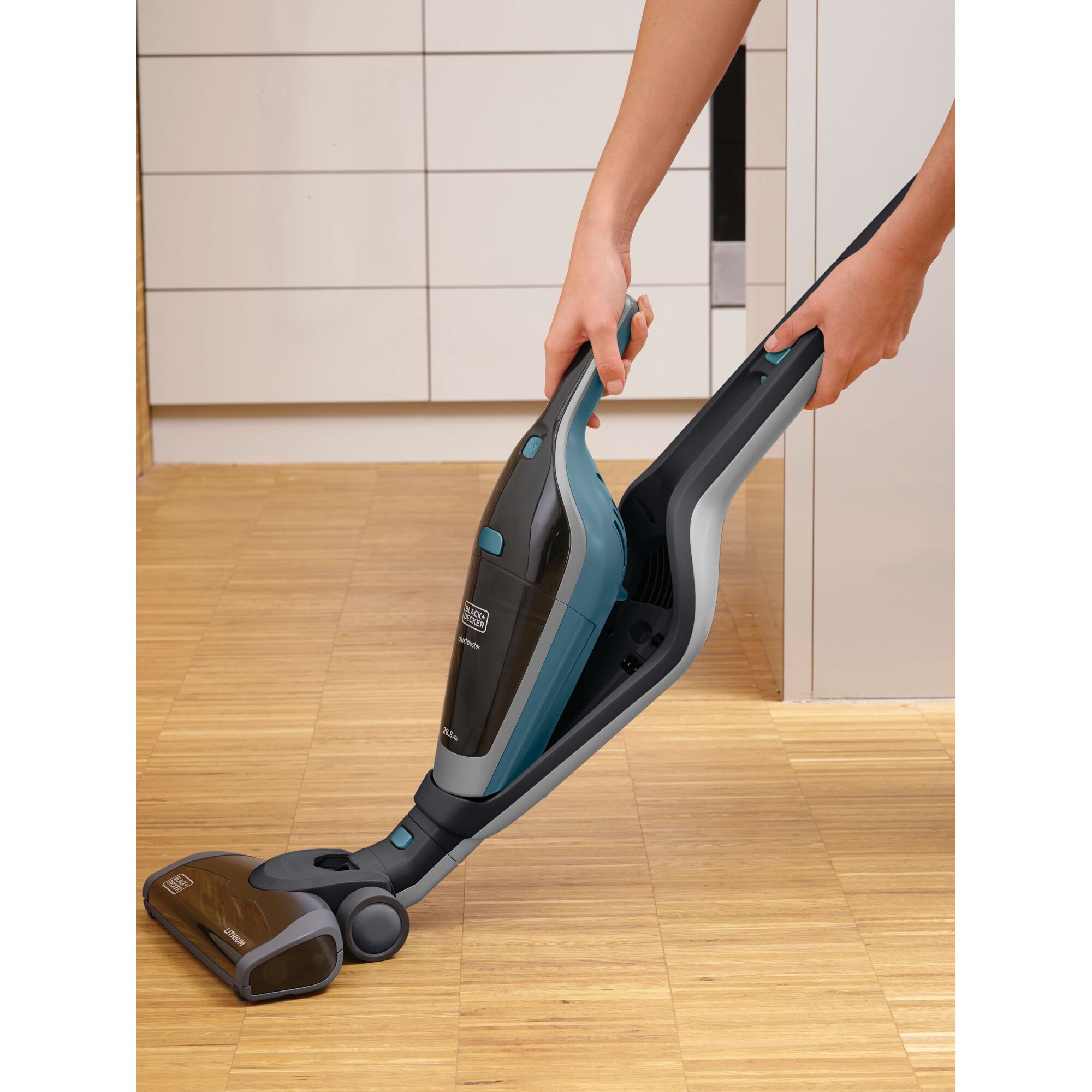 BLACKDECKER SVA420B cordless stick vacuum cleaner in use on light wood flooring indoors.