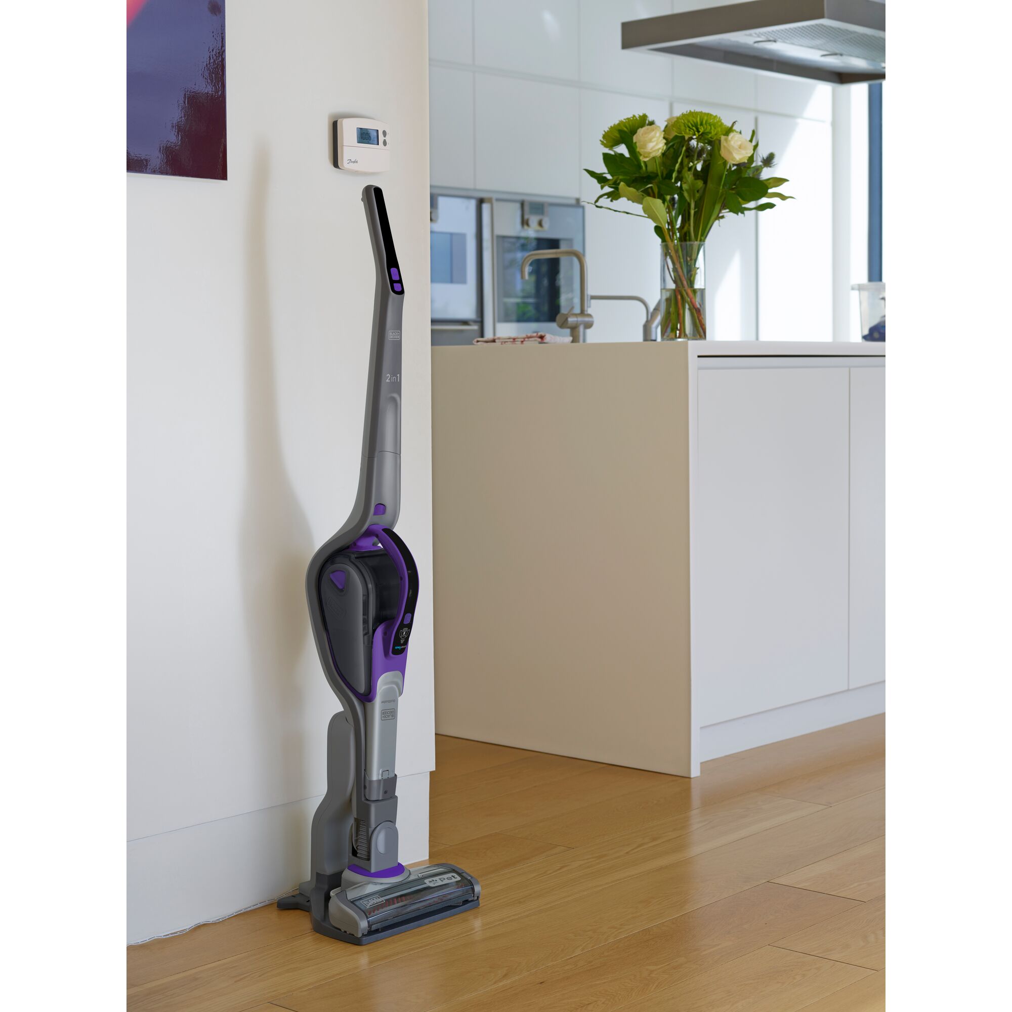 BLACK+DECKER SVJ520BFSP cordless stick vacuum cleaner with purple accents standing upright in a modern kitchen.